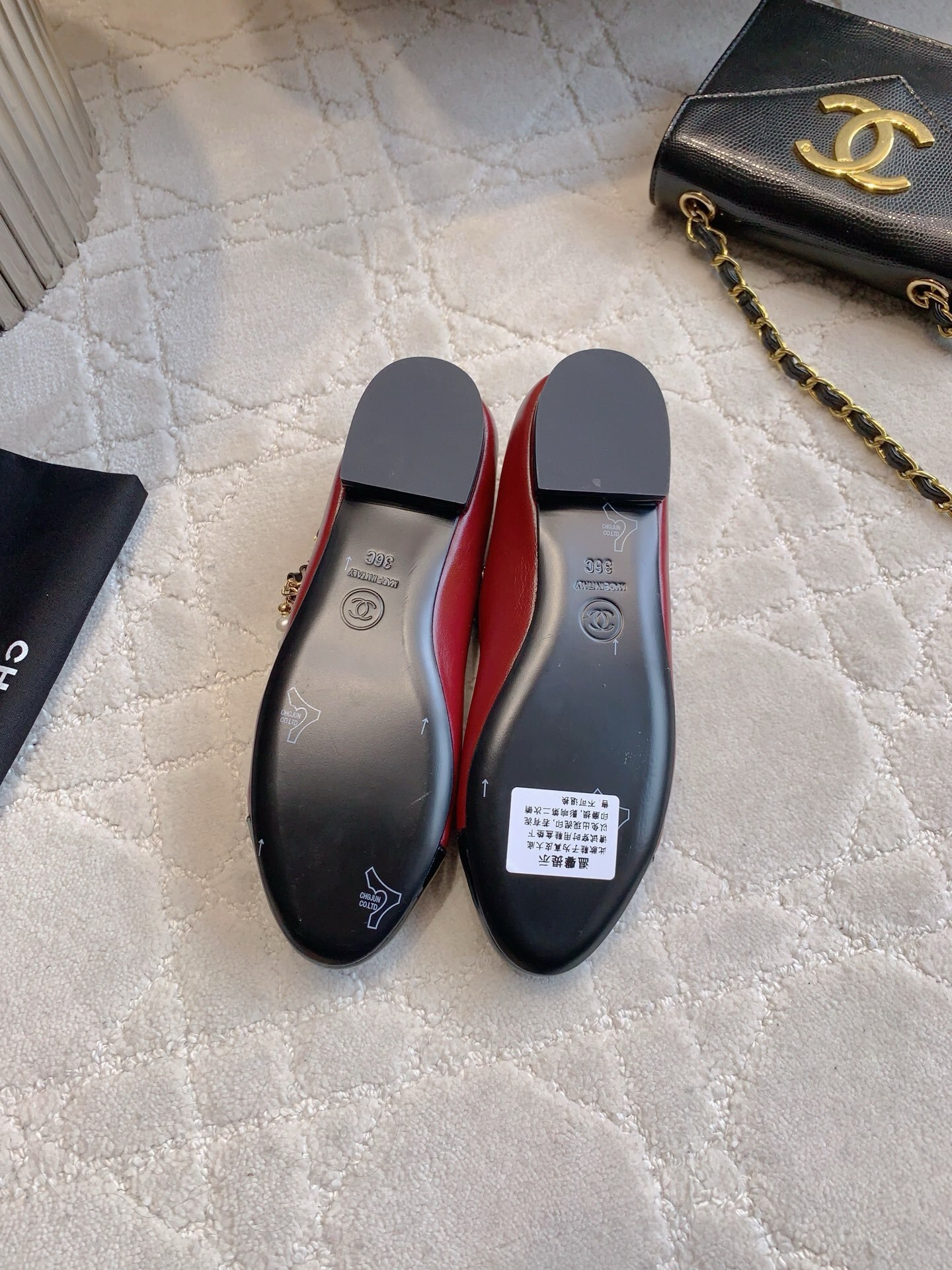 Chanel red leather ballet flats with black patent toe and pearl chain strap on a marble surface. - Hình 6