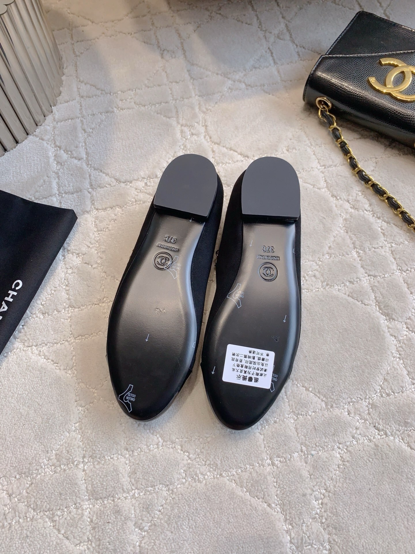 Pair of black Chanel Mary Jane flats with suede body, patent leather cap toe, and gold chain pearl straps on a marble table. - Hình 6