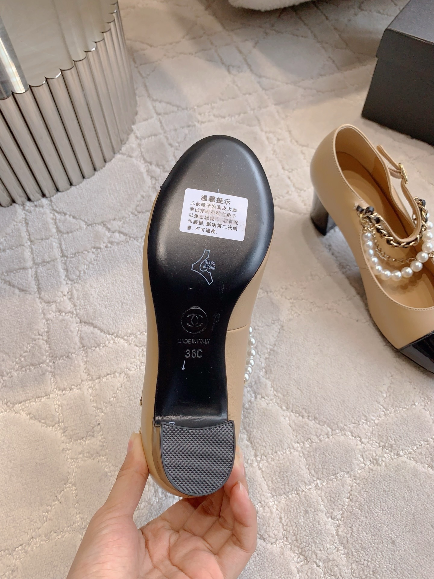 Chanel two-tone beige and black leather Mary Jane pumps with pearl and gold chain details on a marble table - Hình 6