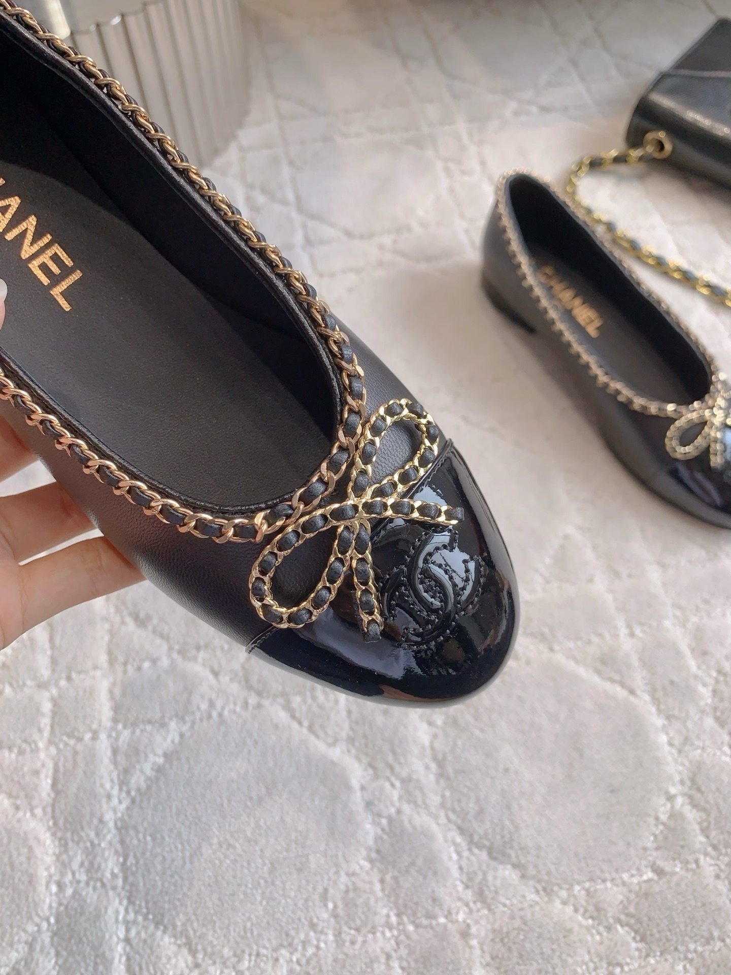Pair of Chanel black leather ballerina flats with gold chain trim and patent leather toe cap on a marble table - Hình 7