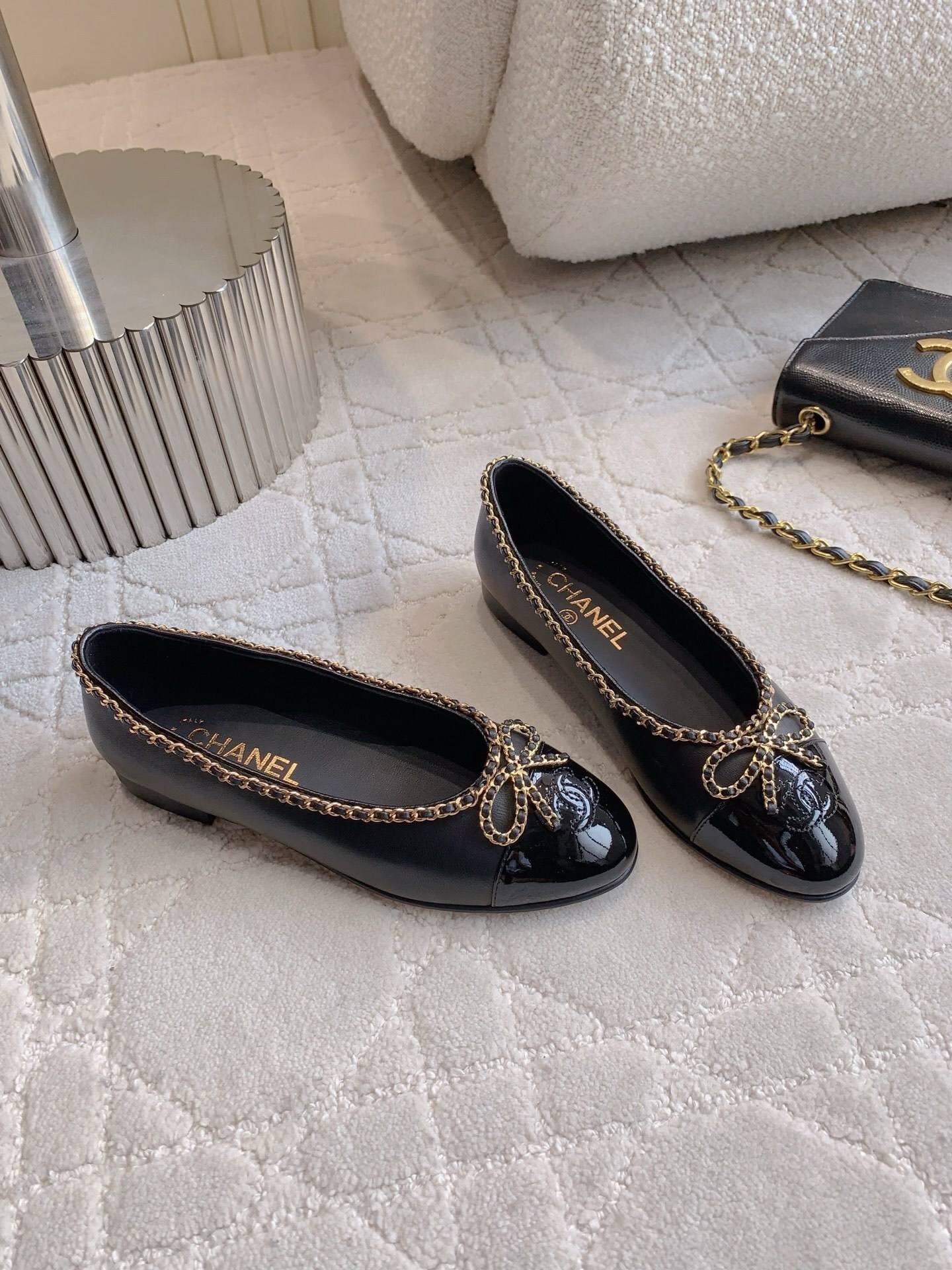 Pair of Chanel black leather ballerina flats with gold chain trim and patent leather toe cap on a marble table - Hình 3