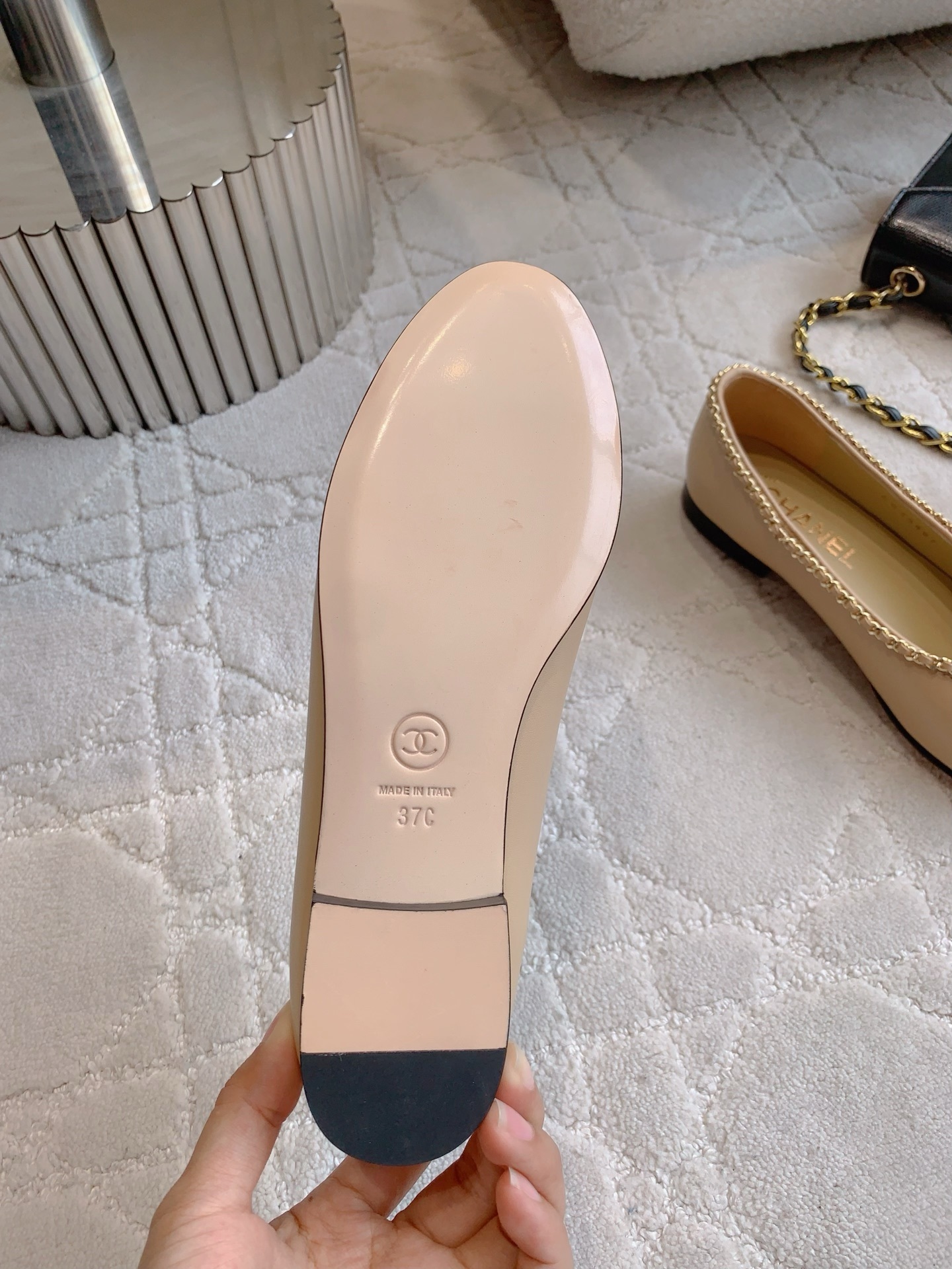 Luxury Chanel beige leather ballerina flats with black patent leather cap toe and gold chain trim detail displayed on a marble surface - Hình 6