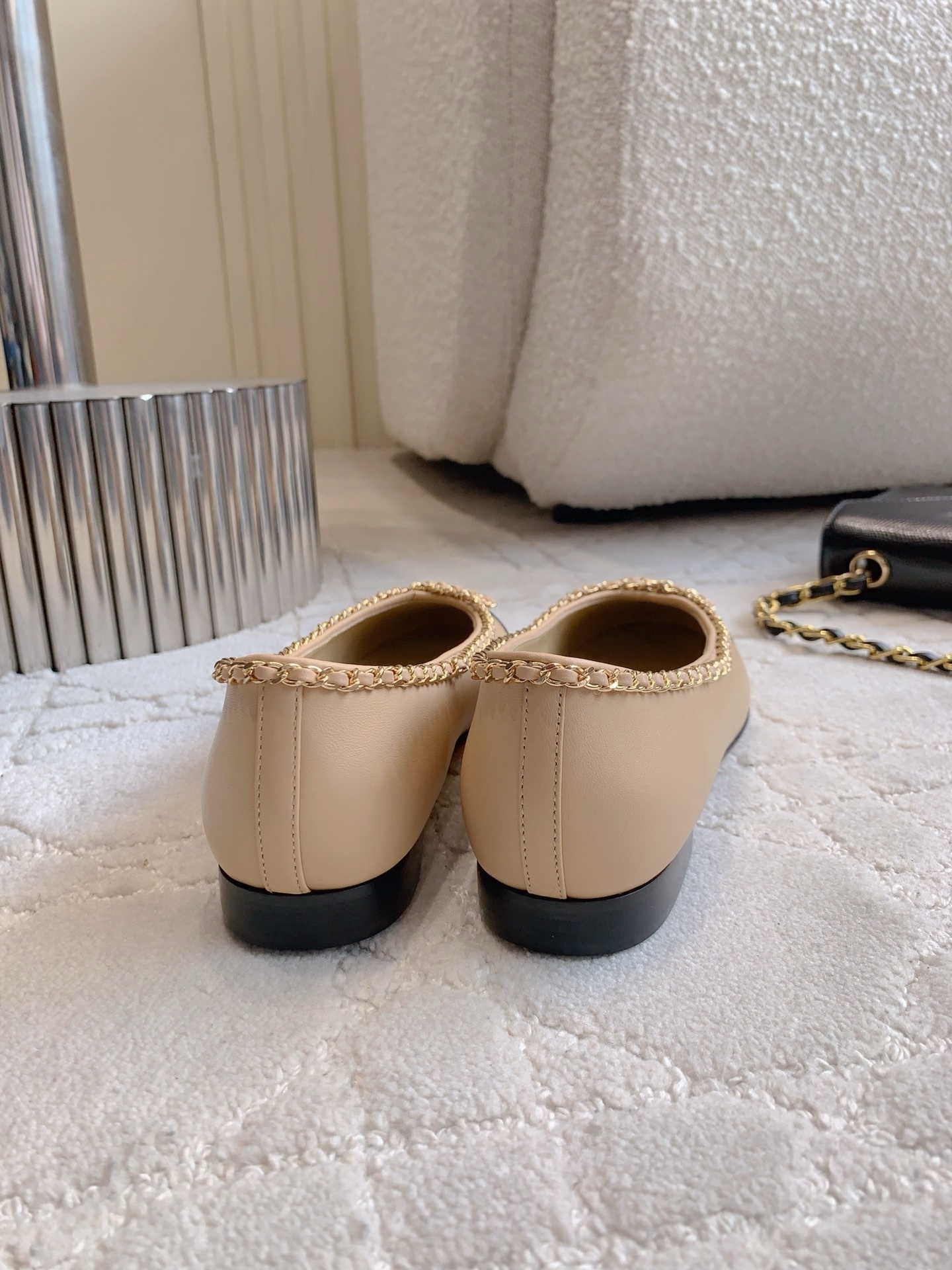Luxury Chanel beige leather ballerina flats with black patent leather cap toe and gold chain trim detail displayed on a marble surface - Hình 5
