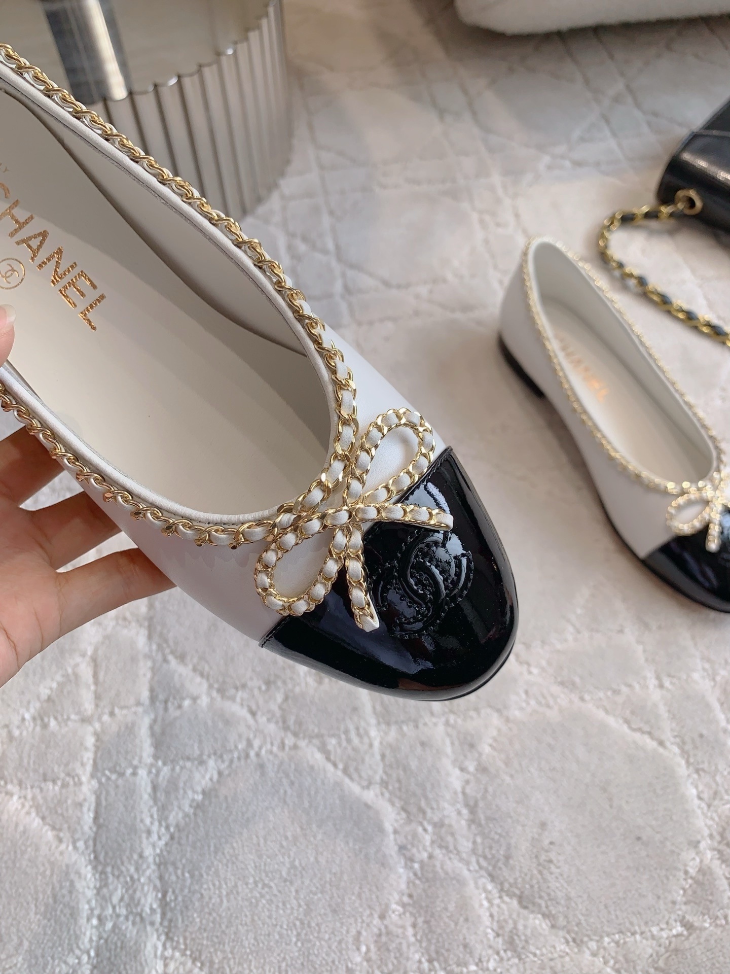 Luxury Chanel white leather ballerina flats with black patent cap-toe and gold chain link bow detailing. - Hình 7