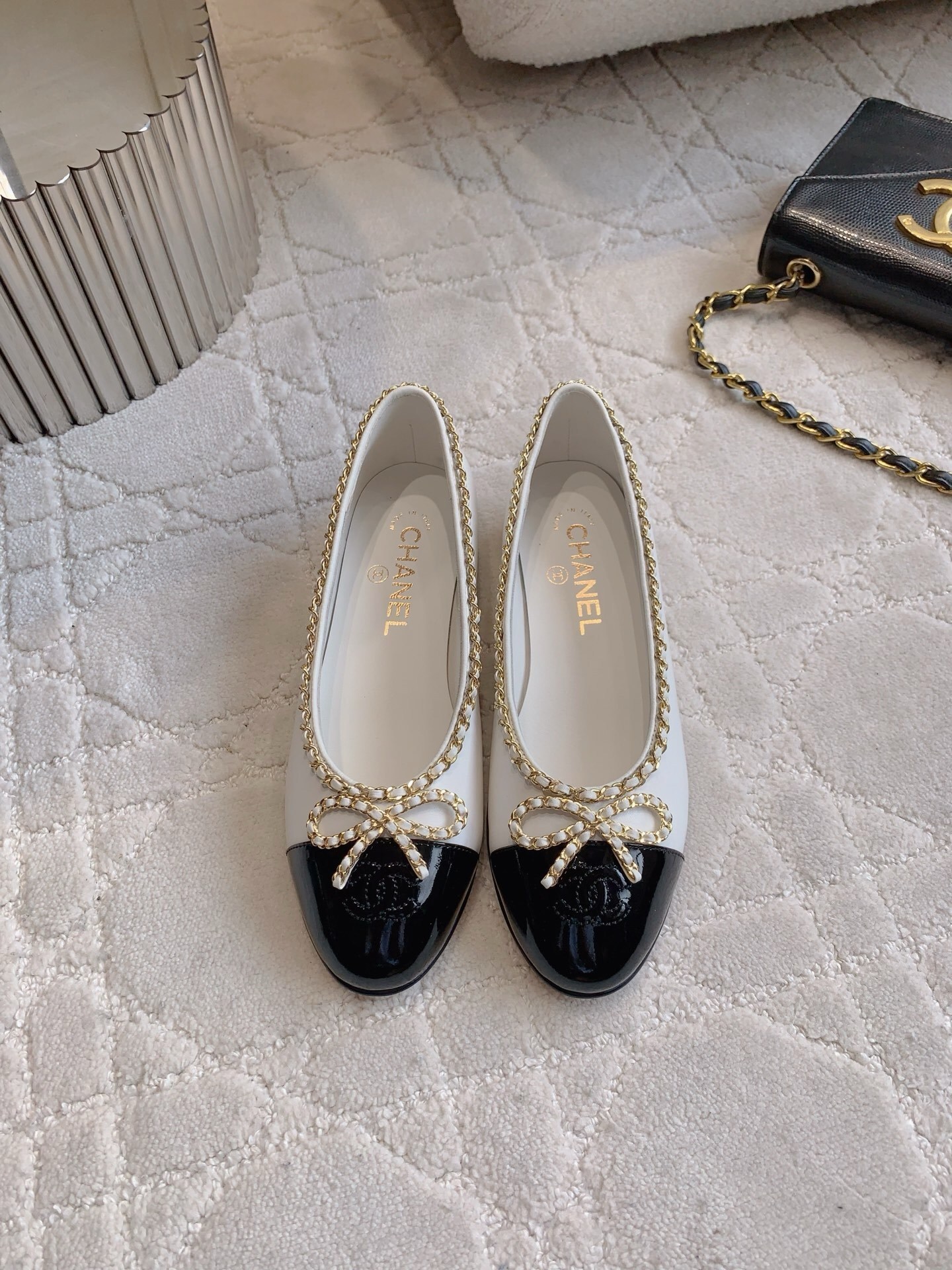 Luxury Chanel white leather ballerina flats with black patent cap-toe and gold chain link bow detailing. - Hình 2