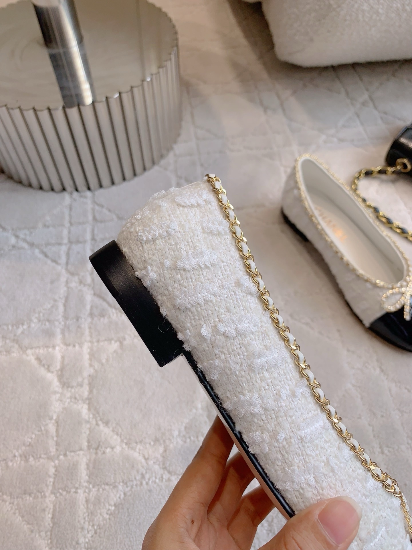 Pair of Chanel white tweed ballet flats with black patent leather cap toes and gold chain bow detailing on a white carpet - Hình 9