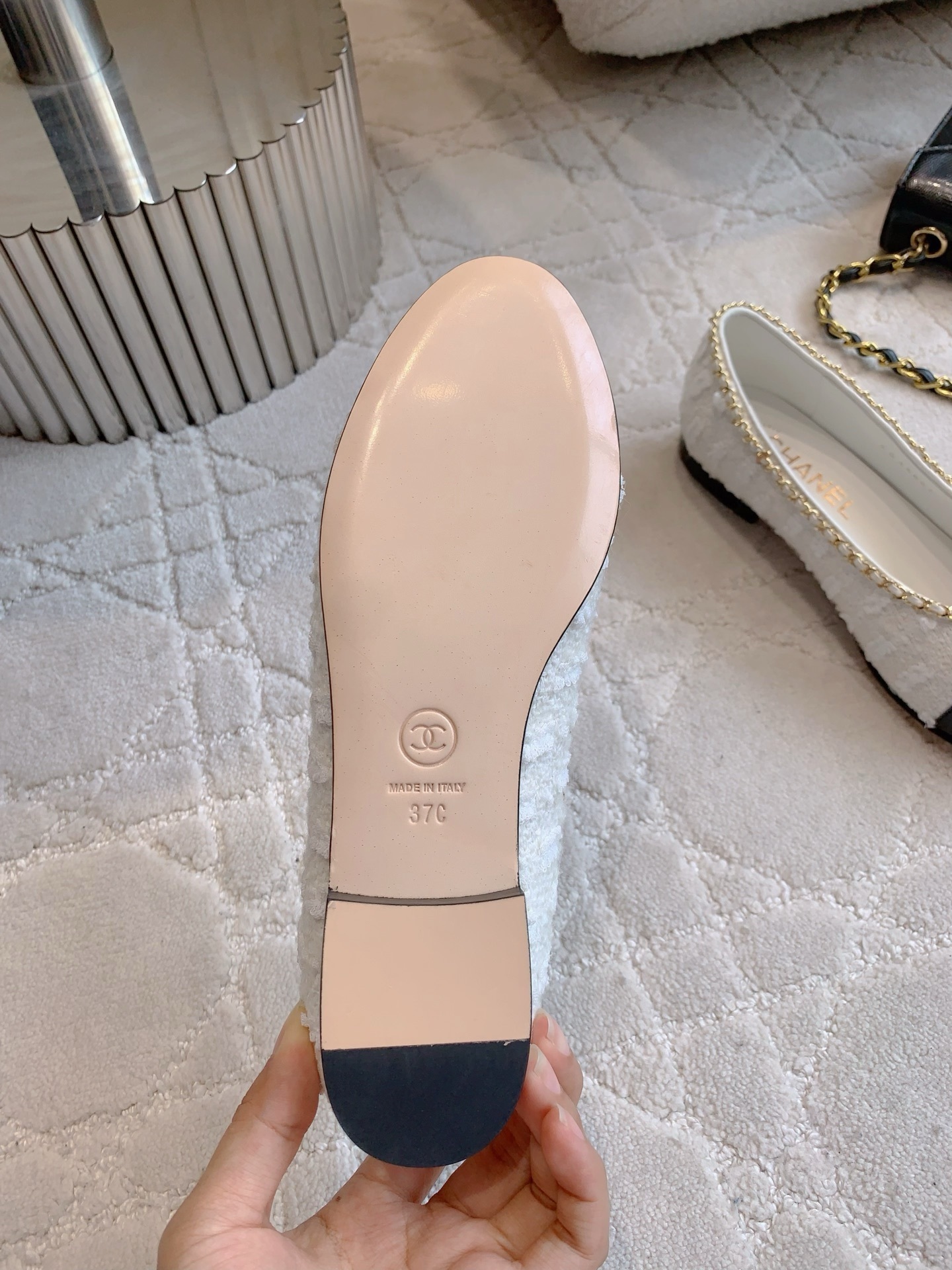 Pair of Chanel white tweed ballet flats with black patent leather cap toes and gold chain bow detailing on a white carpet - Hình 6