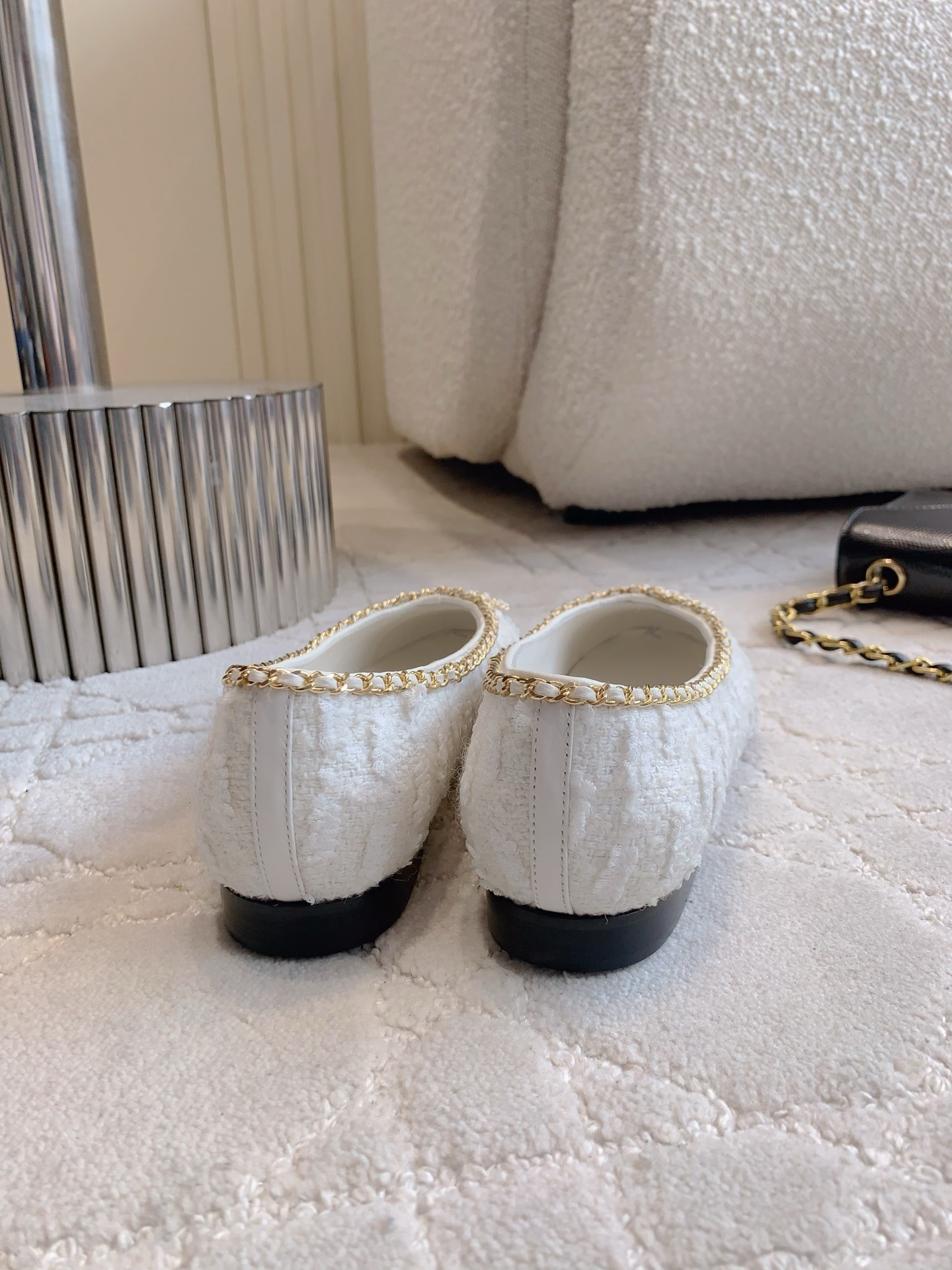 Pair of Chanel white tweed ballet flats with black patent leather cap toes and gold chain bow detailing on a white carpet - Hình 5