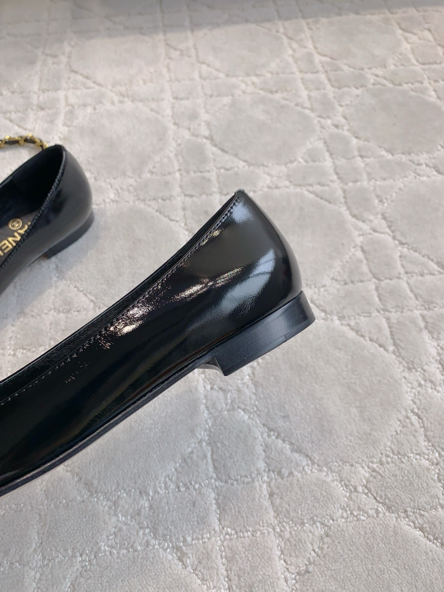 Pair of black Chanel patent leather ballet flats with gold chain and CC logo detailing on a marble surface - Hình 9