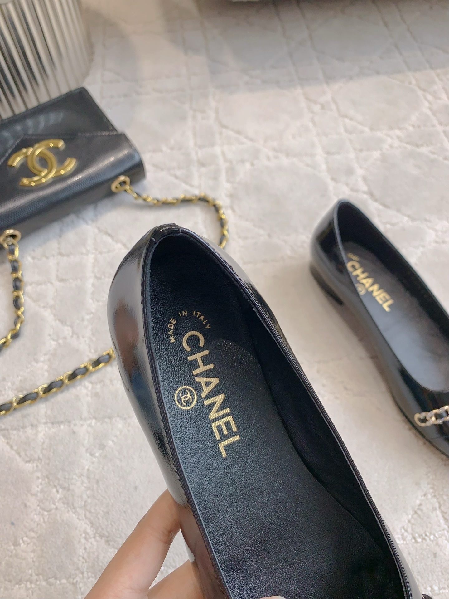 Pair of black Chanel patent leather ballet flats with gold chain and CC logo detailing on a marble surface - Hình 8