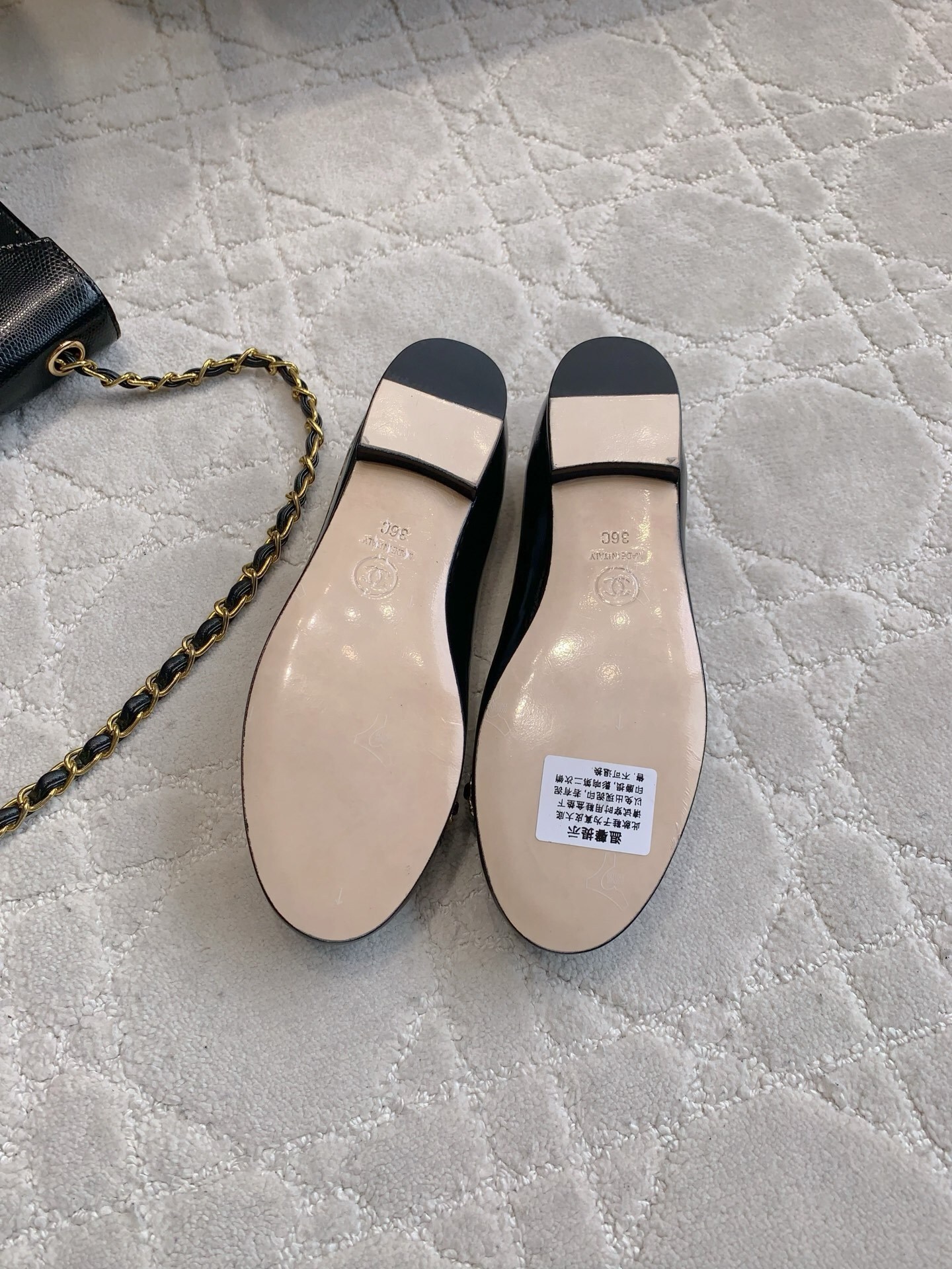 Pair of black Chanel patent leather ballet flats with gold chain and CC logo detailing on a marble surface - Hình 6