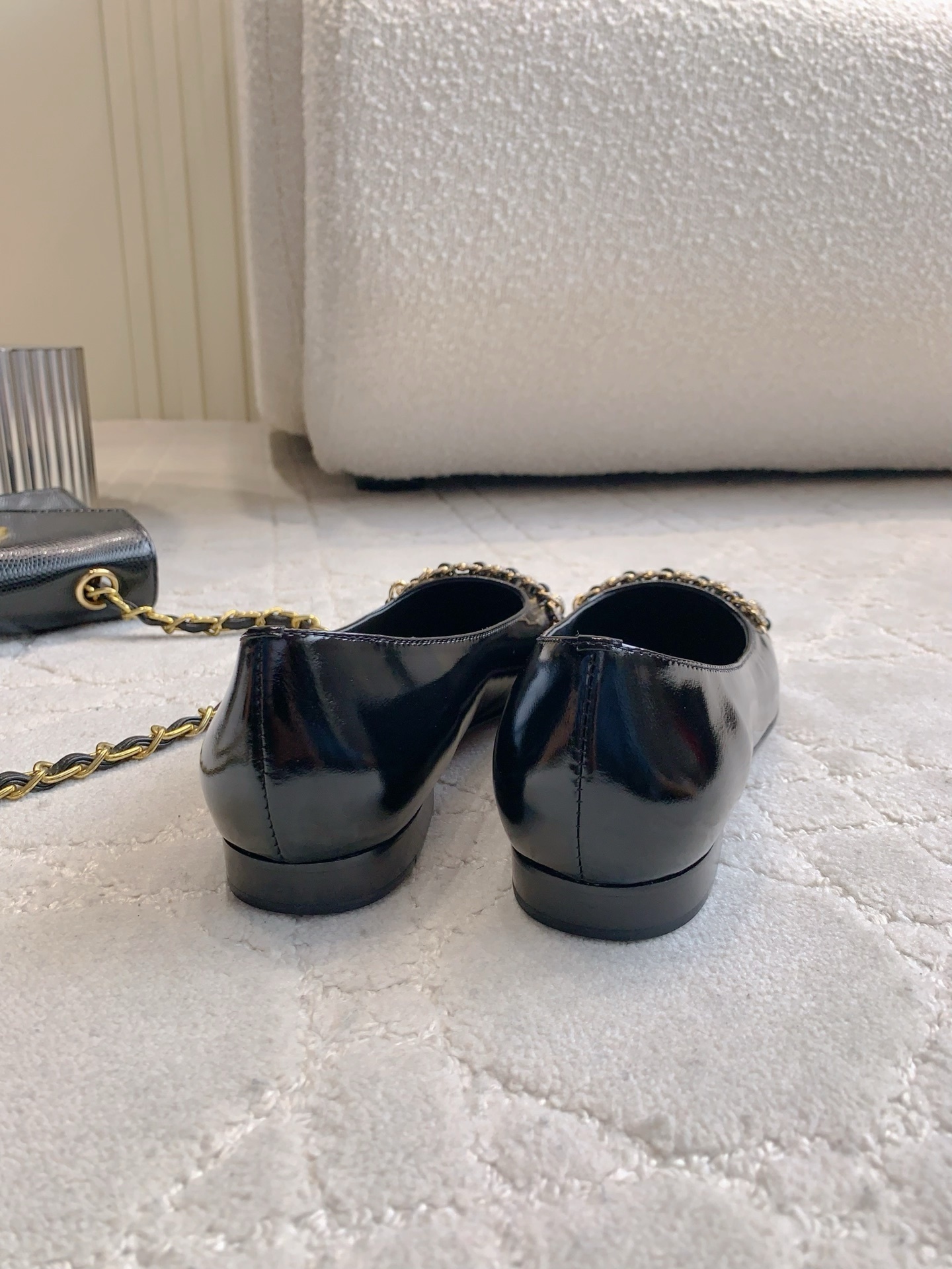 Pair of black Chanel patent leather ballet flats with gold chain and CC logo detailing on a marble surface - Hình 5