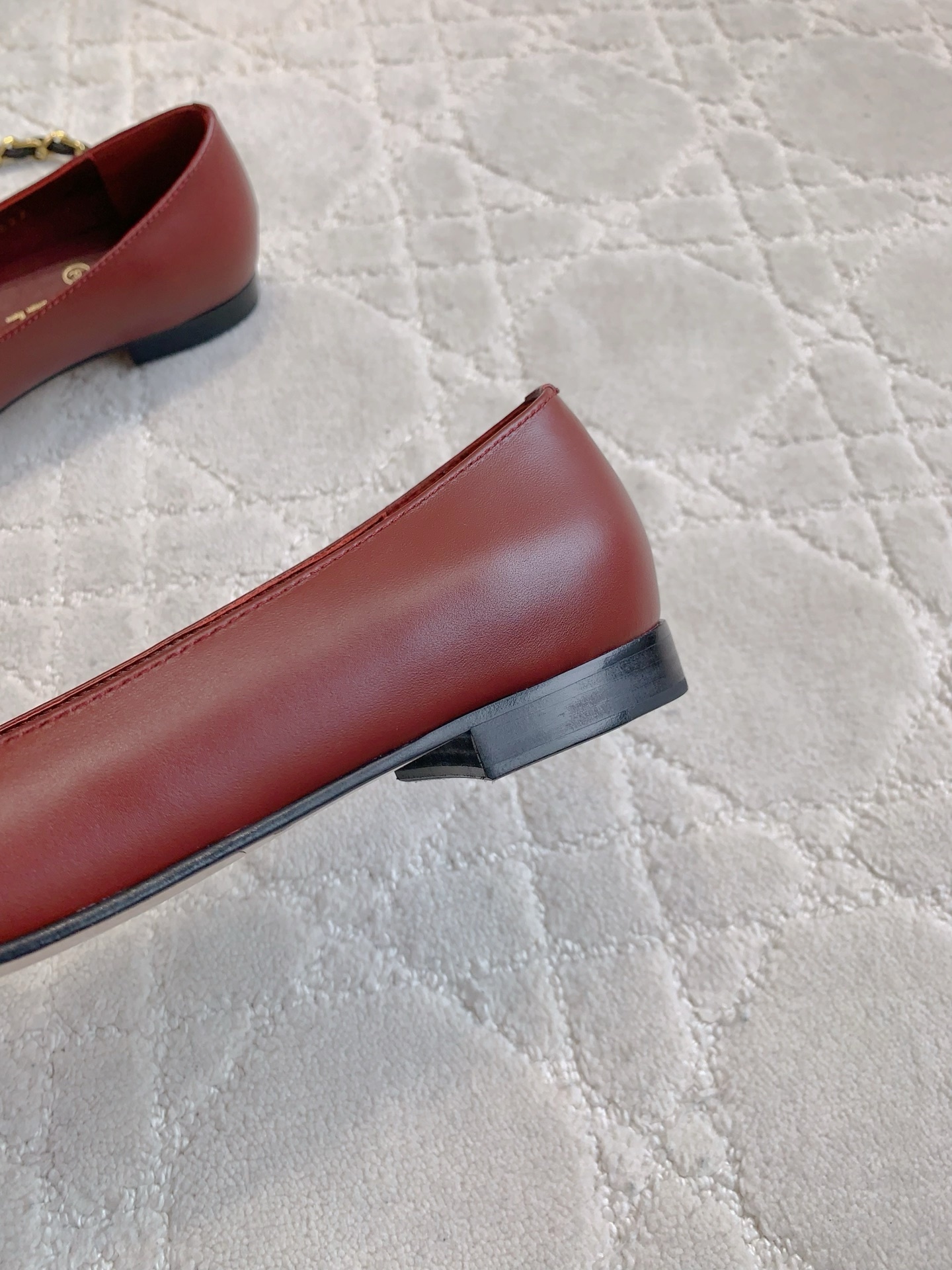 Luxury burgundy red Chanel leather ballet flats with gold chain and CC logo detail on a marble table. - Hình 9