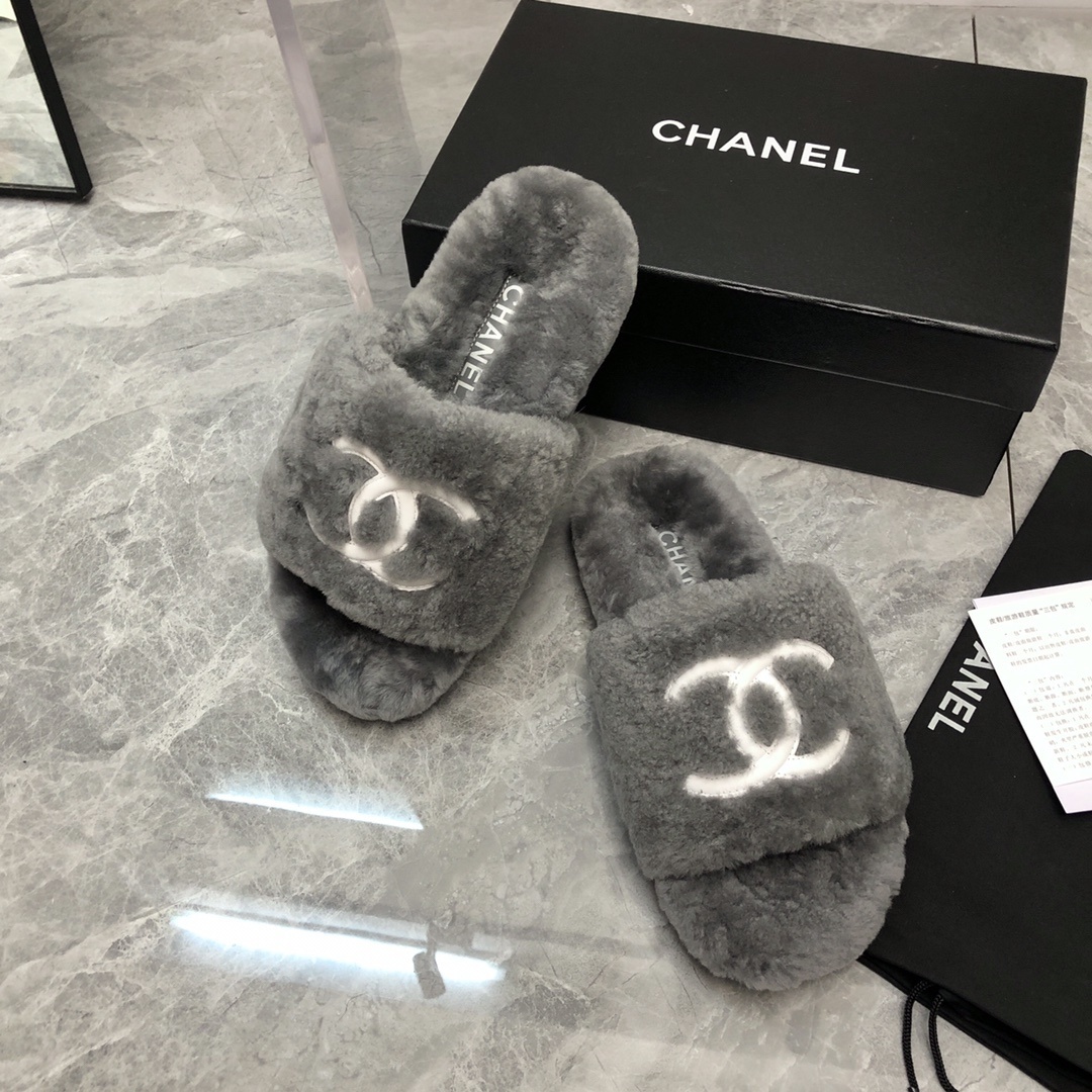 Pair of gray Chanel shearling fur slides with white CC logo on a glass table with original box and dust bag. - Hình 8