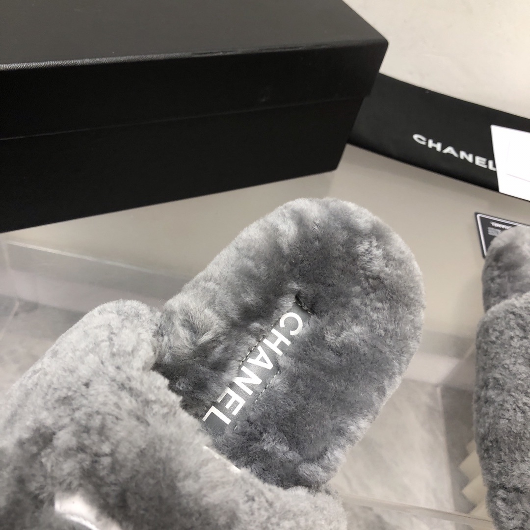 Pair of gray Chanel shearling fur slides with white CC logo on a glass table with original box and dust bag. - Hình 6