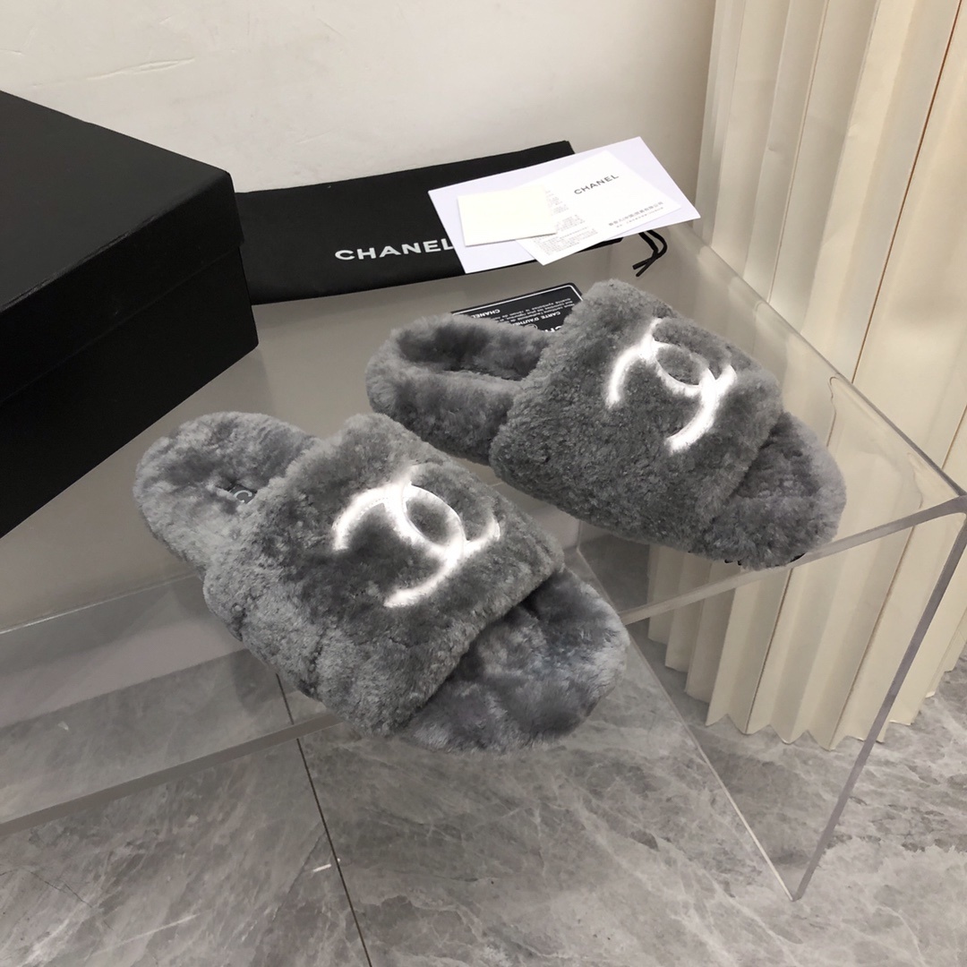 Pair of gray Chanel shearling fur slides with white CC logo on a glass table with original box and dust bag. - Hình 2