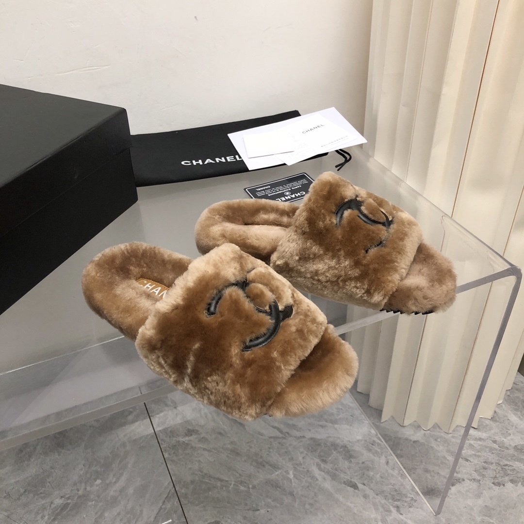 A pair of luxury tan Chanel shearling fur slides with black CC logo, displayed with original box and authenticity card. - Hình 2