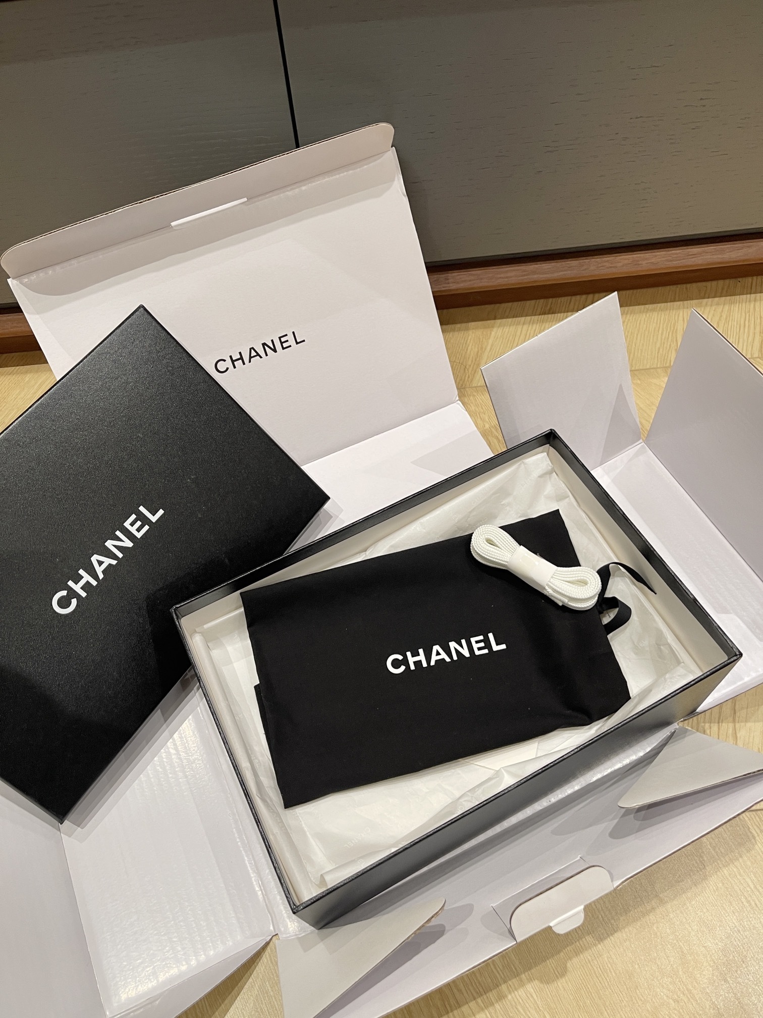 Pair of black Chanel sneakers in patent leather and suede with a gum sole, featuring the interlocking CC logo on the side. - Hình 8