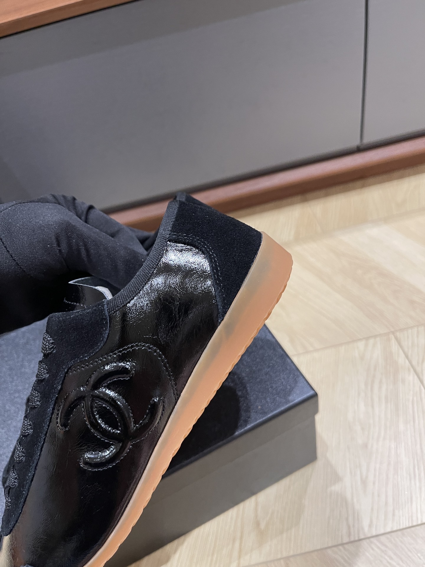 Pair of black Chanel sneakers in patent leather and suede with a gum sole, featuring the interlocking CC logo on the side. - Hình 6