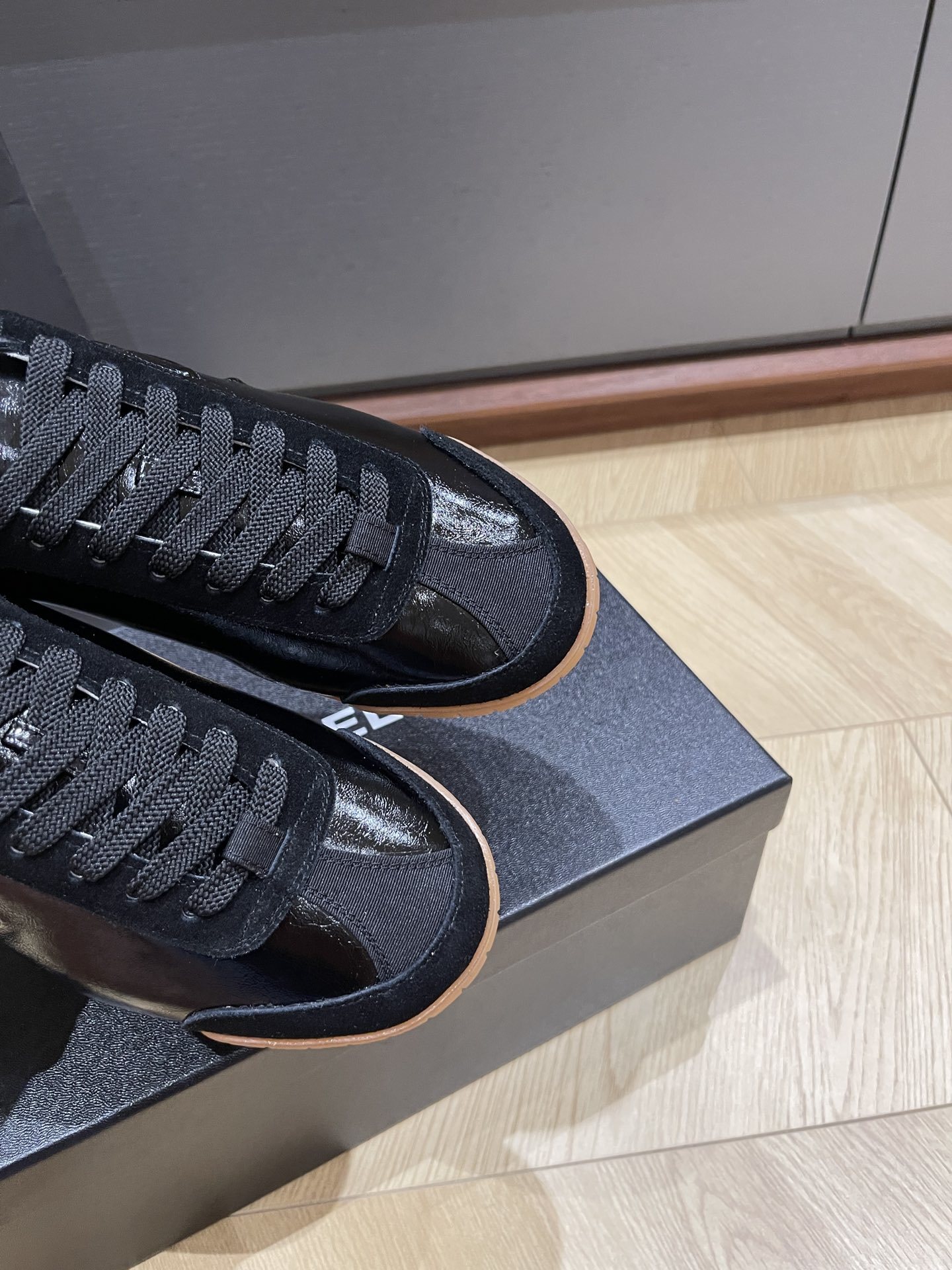 Pair of black Chanel sneakers in patent leather and suede with a gum sole, featuring the interlocking CC logo on the side. - Hình 4