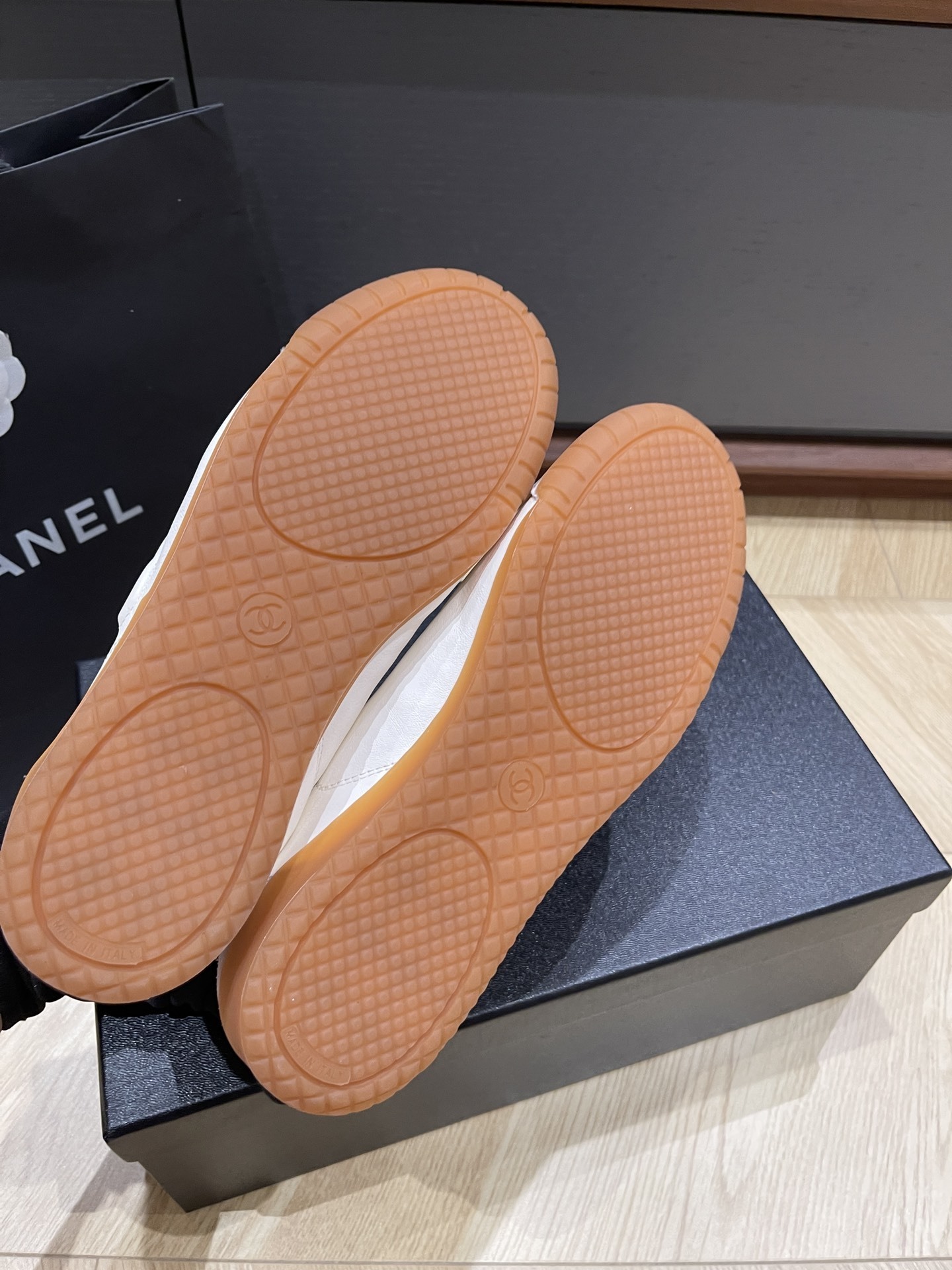 Chanel white calfskin and suede low-top sneakers with gum sole and CC logo resting on a black designer box. - Hình 8