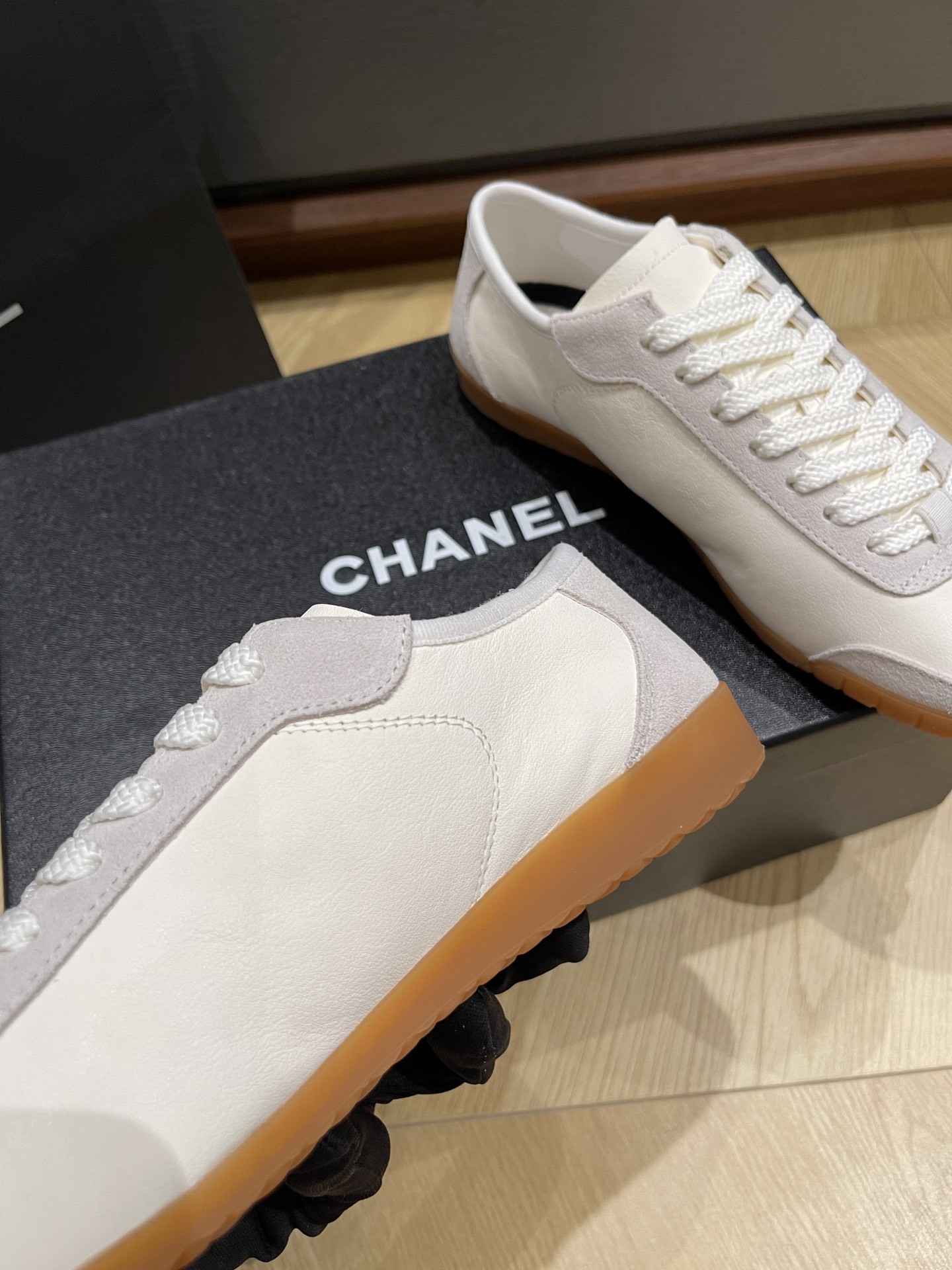 Chanel white calfskin and suede low-top sneakers with gum sole and CC logo resting on a black designer box. - Hình 6