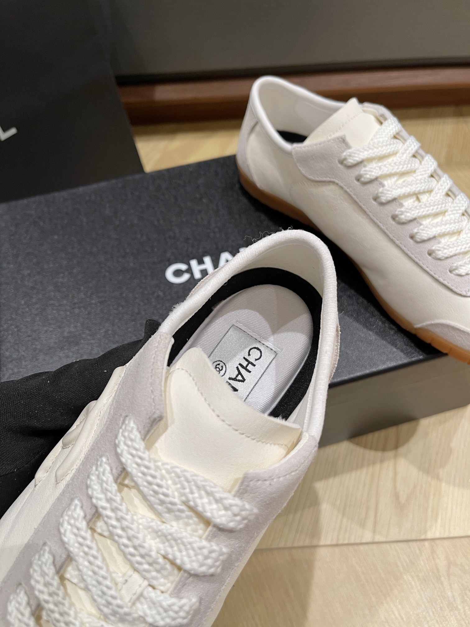 Chanel white calfskin and suede low-top sneakers with gum sole and CC logo resting on a black designer box. - Hình 5