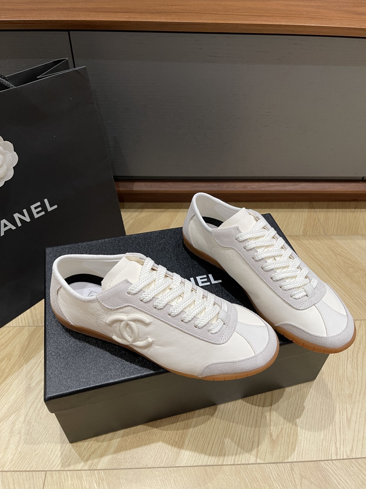 Chanel white calfskin and suede low-top sneakers with gum sole and CC logo resting on a black designer box. - Hình 2