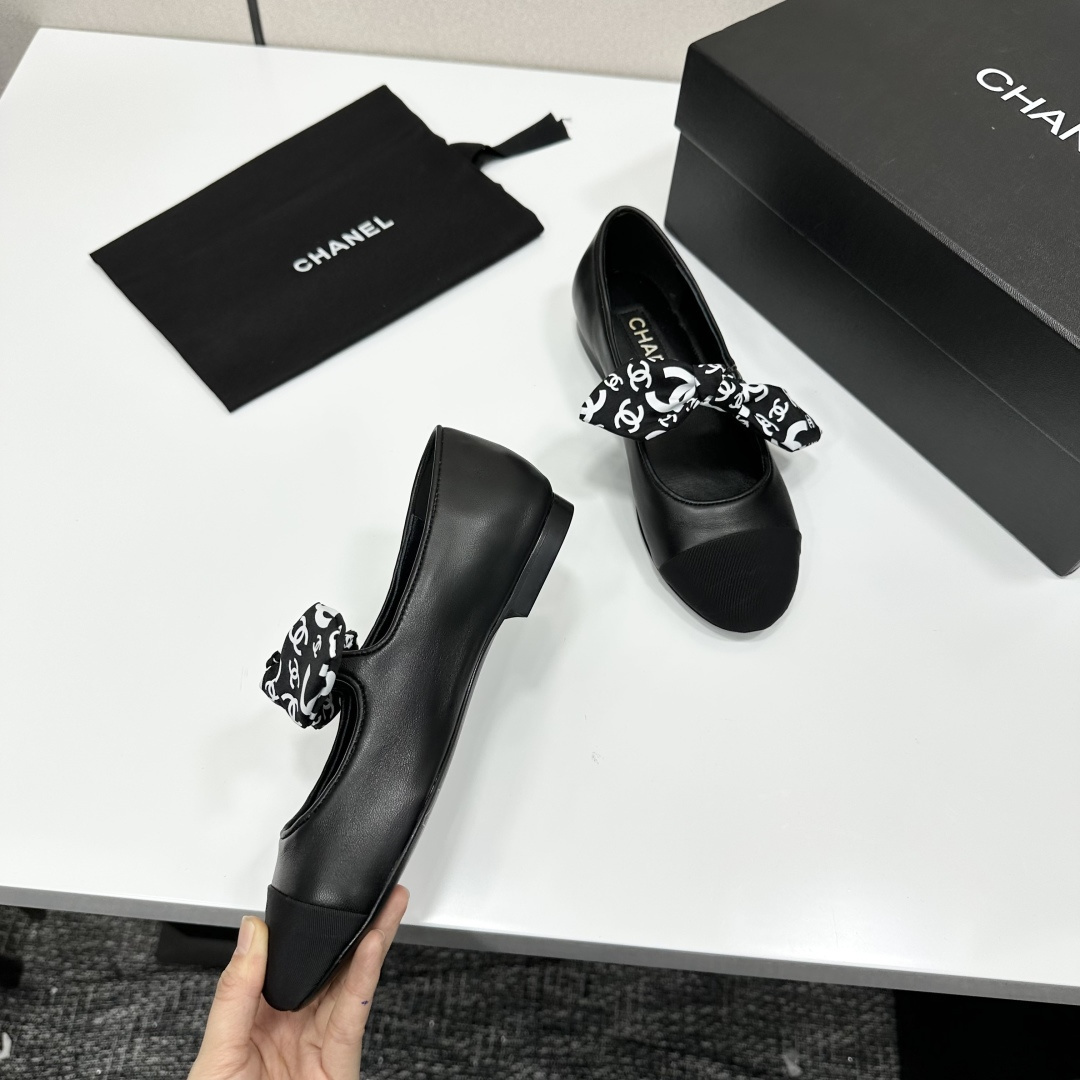 Elegant black Mary Jane ballet flats with a black and white logo pattern bow and fabric cap toe displayed on a luxury black box. - Hình 10