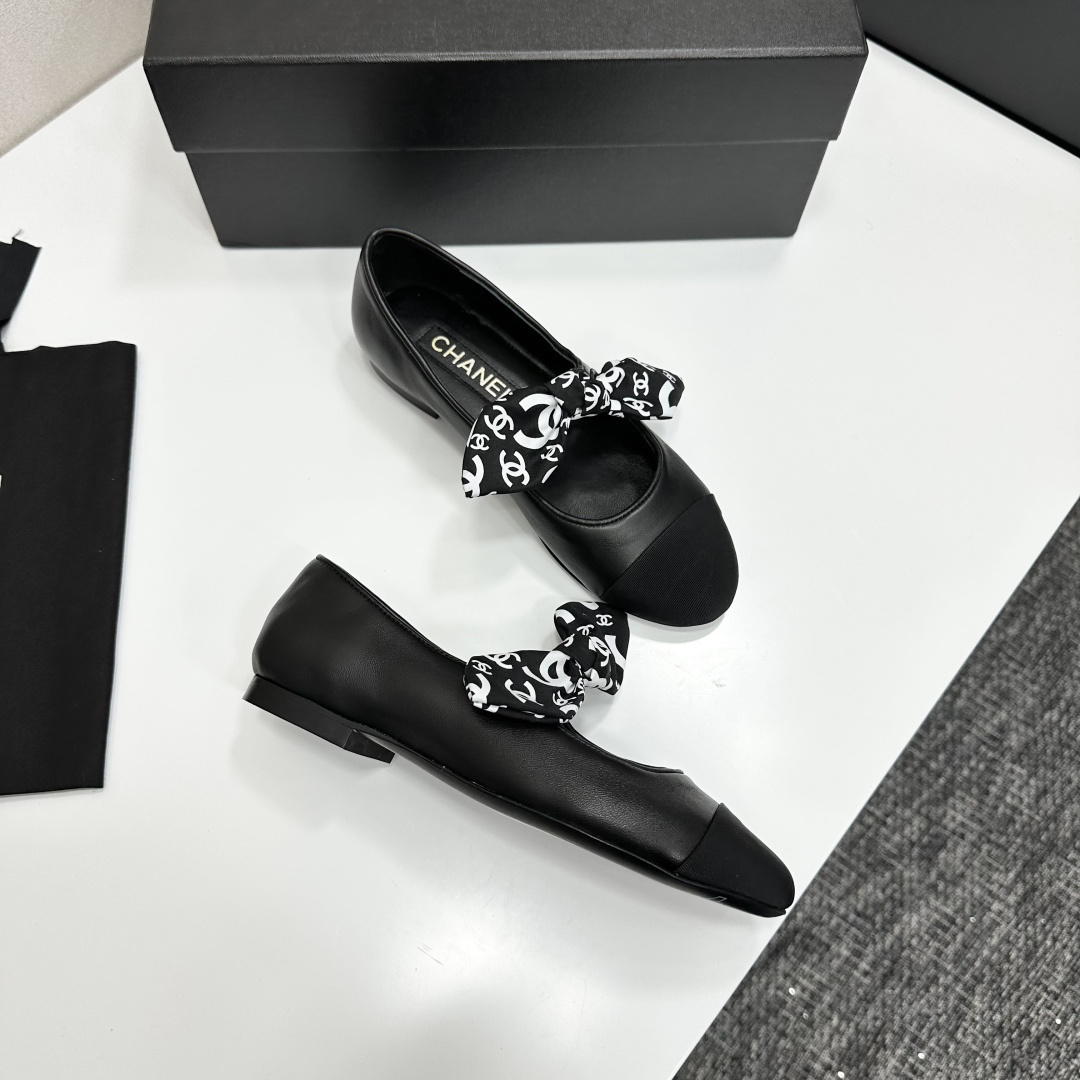 Elegant black Mary Jane ballet flats with a black and white logo pattern bow and fabric cap toe displayed on a luxury black box. - Hình 9