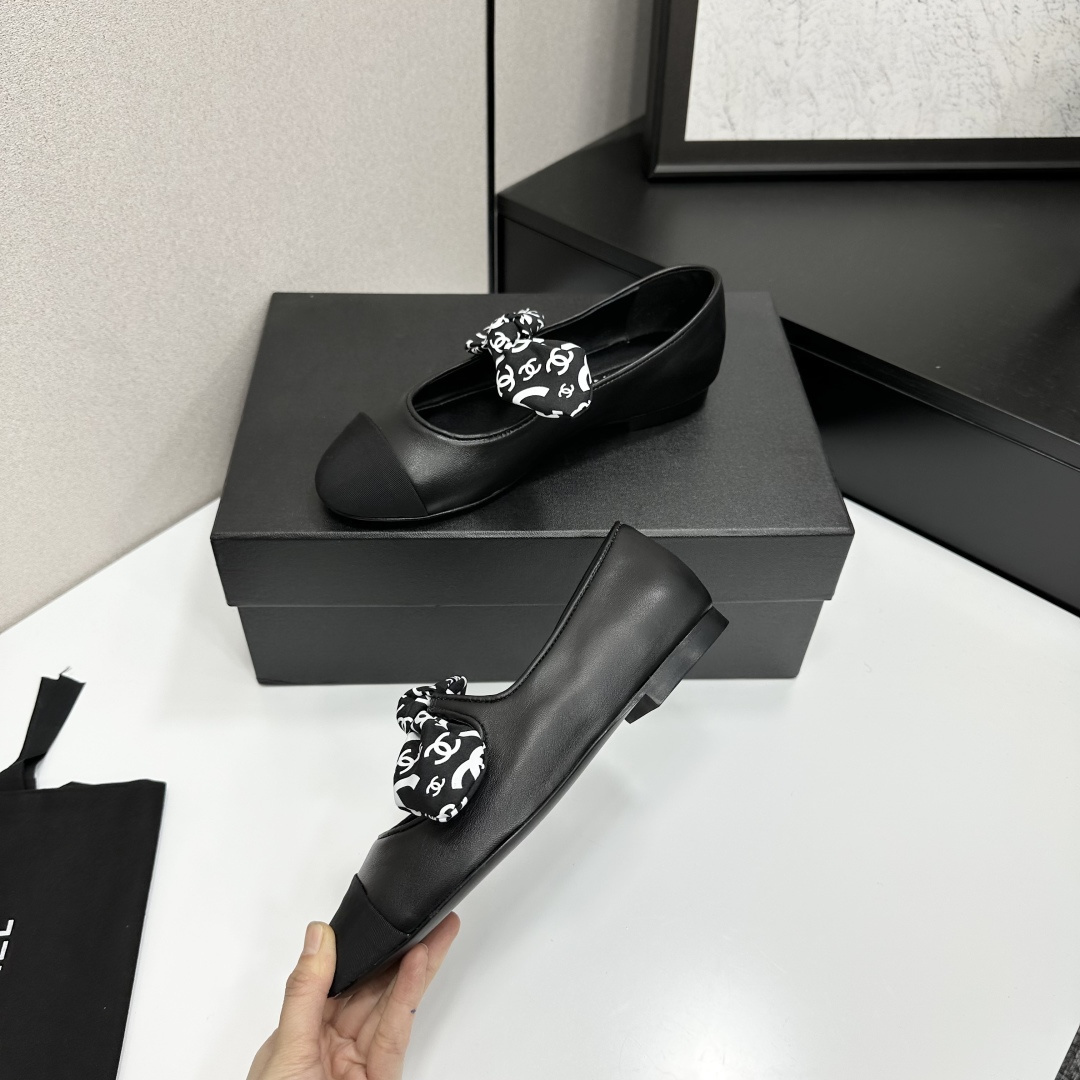 Elegant black Mary Jane ballet flats with a black and white logo pattern bow and fabric cap toe displayed on a luxury black box. - Hình 4