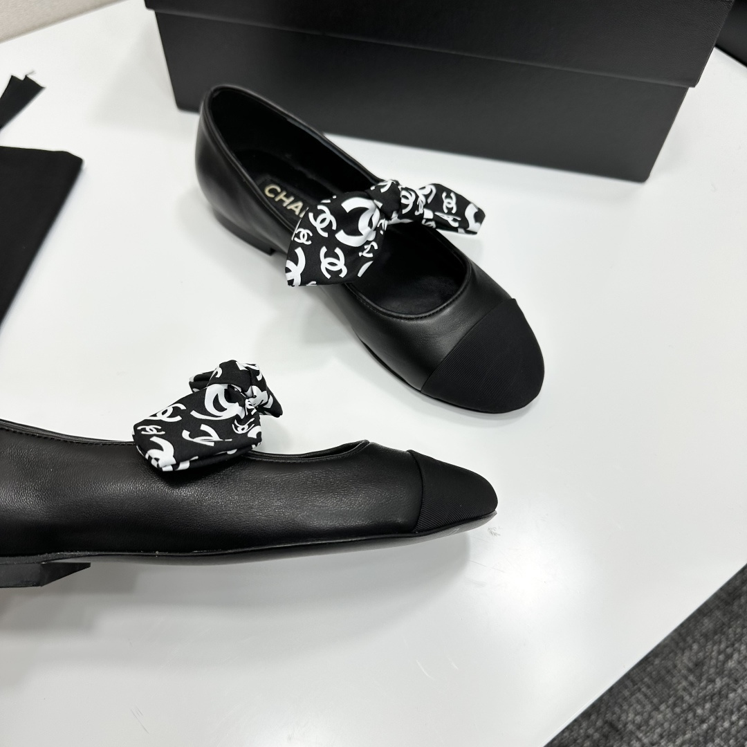 Elegant black Mary Jane ballet flats with a black and white logo pattern bow and fabric cap toe displayed on a luxury black box. - Hình 2