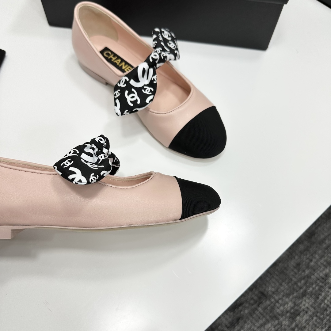 Pair of light pink luxury ballerina flats with black toe caps and patterned bows on a black display box - Hình 9