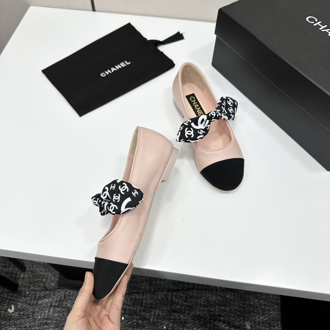 Pair of light pink luxury ballerina flats with black toe caps and patterned bows on a black display box - Hình 8