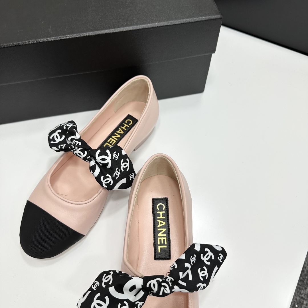 Pair of light pink luxury ballerina flats with black toe caps and patterned bows on a black display box - Hình 7