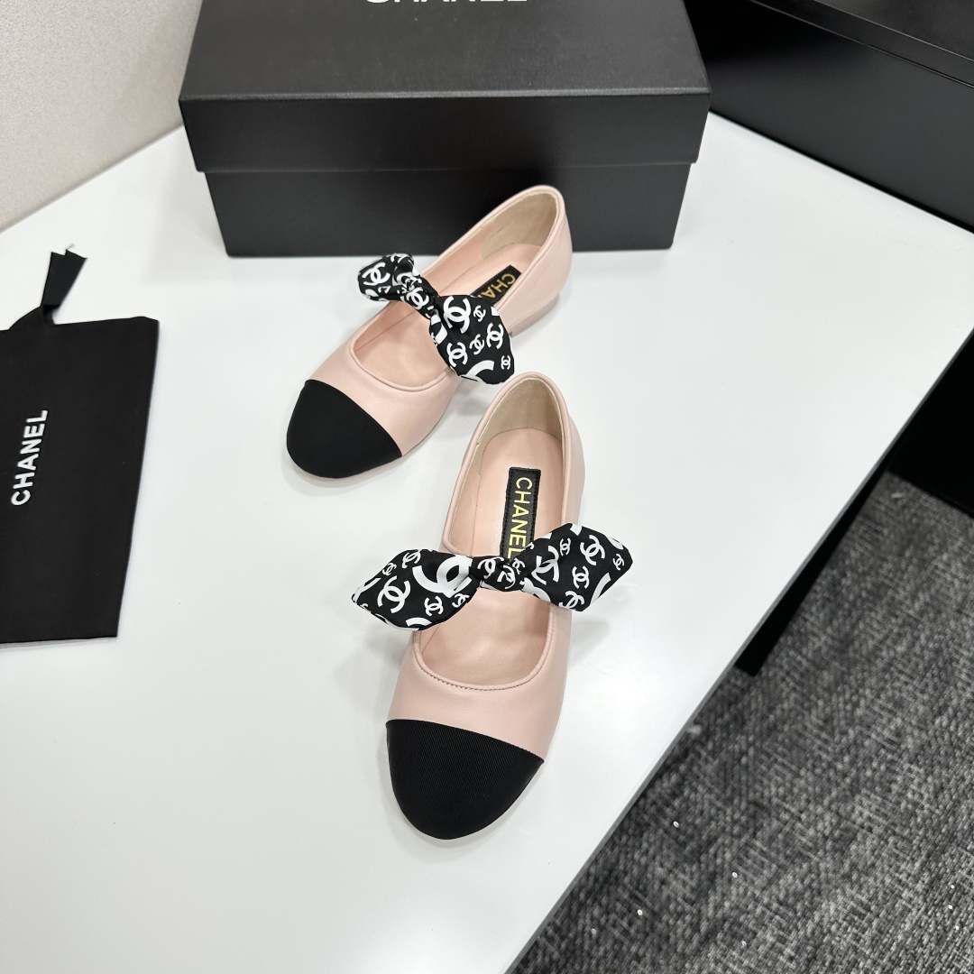 Pair of light pink luxury ballerina flats with black toe caps and patterned bows on a black display box - Hình 5