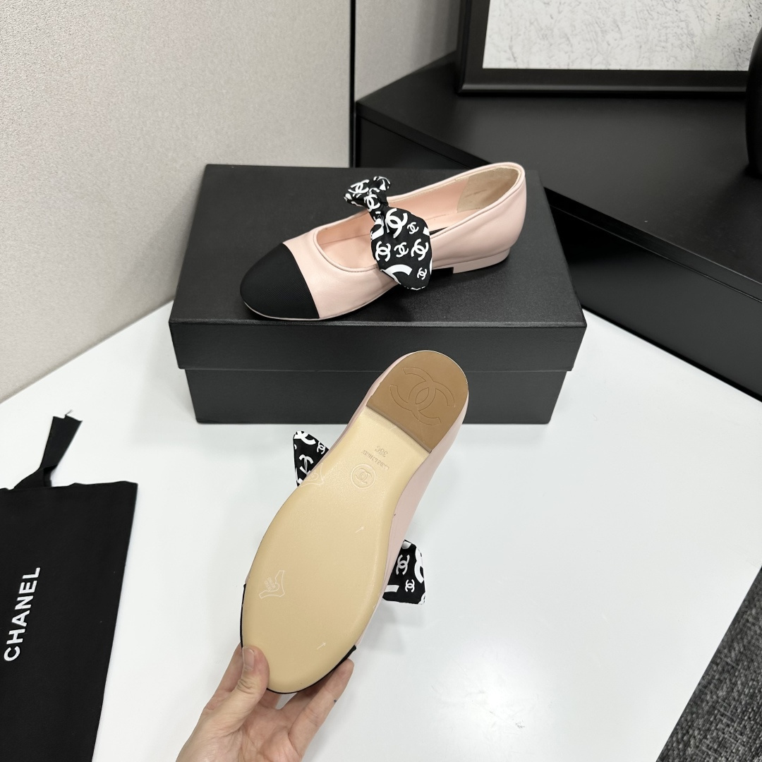 Pair of light pink luxury ballerina flats with black toe caps and patterned bows on a black display box - Hình 4