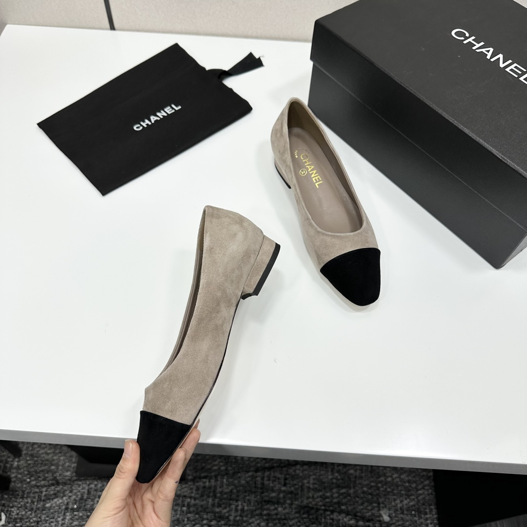 Chanel two-tone beige suede ballerina flats with black toe cap and gold CC logo on the heel sitting on a black box. - Hình 3