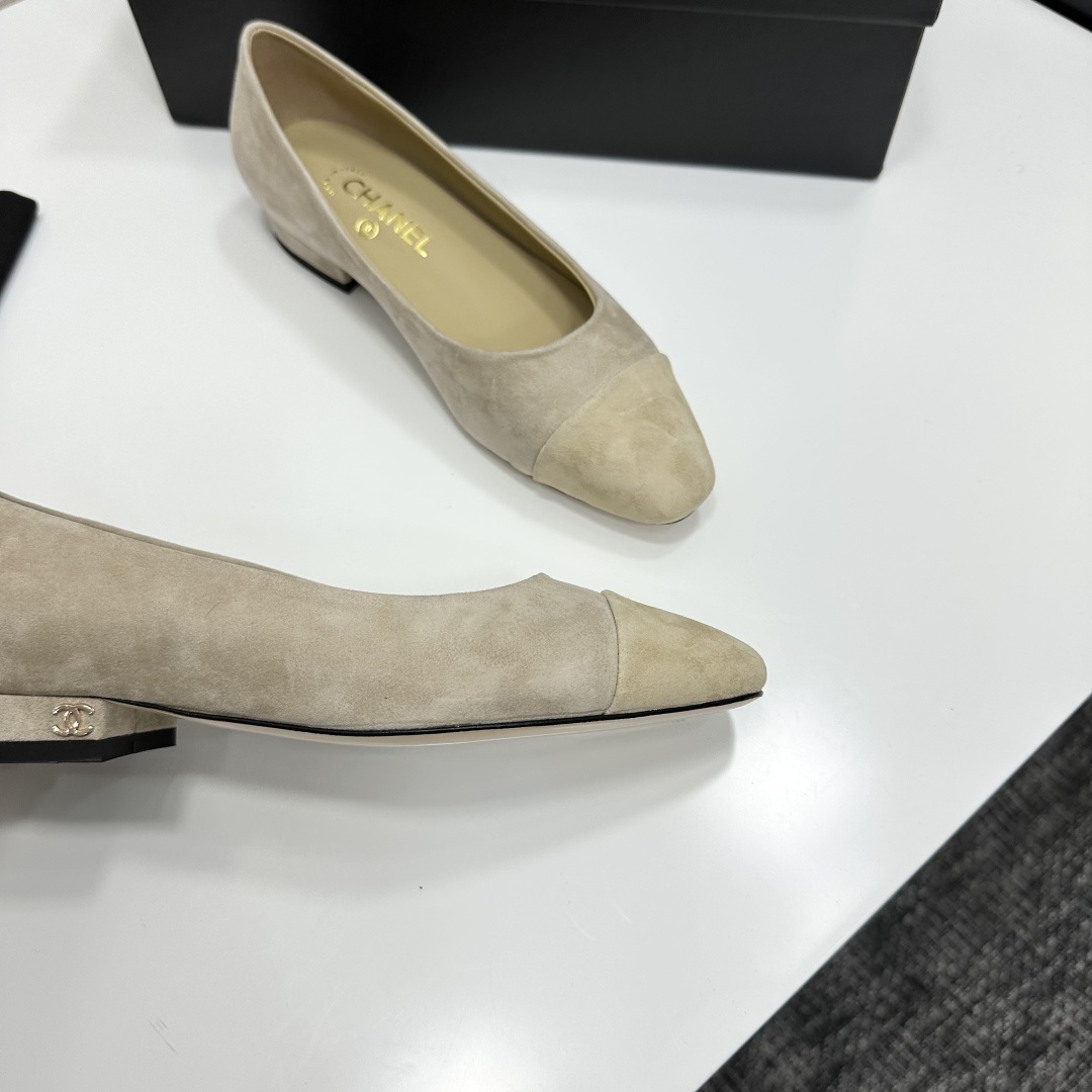 A pair of Chanel beige suede cap-toe pumps with a small block heel featuring a gold CC logo, displayed on a black box. - Hình 8