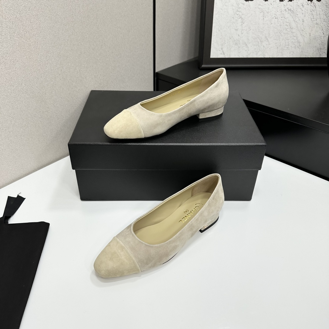 A pair of Chanel beige suede cap-toe pumps with a small block heel featuring a gold CC logo, displayed on a black box. - Hình 2