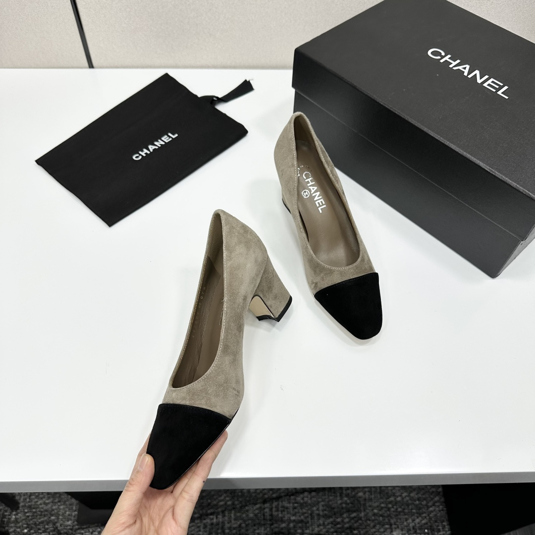 Chanel beige suede pumps with black cap-toes and block heels displayed on a black Chanel box. - Hình 2