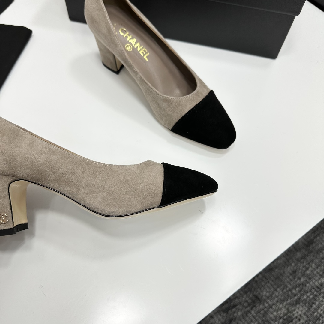 Elegant beige suede pumps with a black toe cap and gold logo on the block heel, displayed on a black designer box. - Hình 9