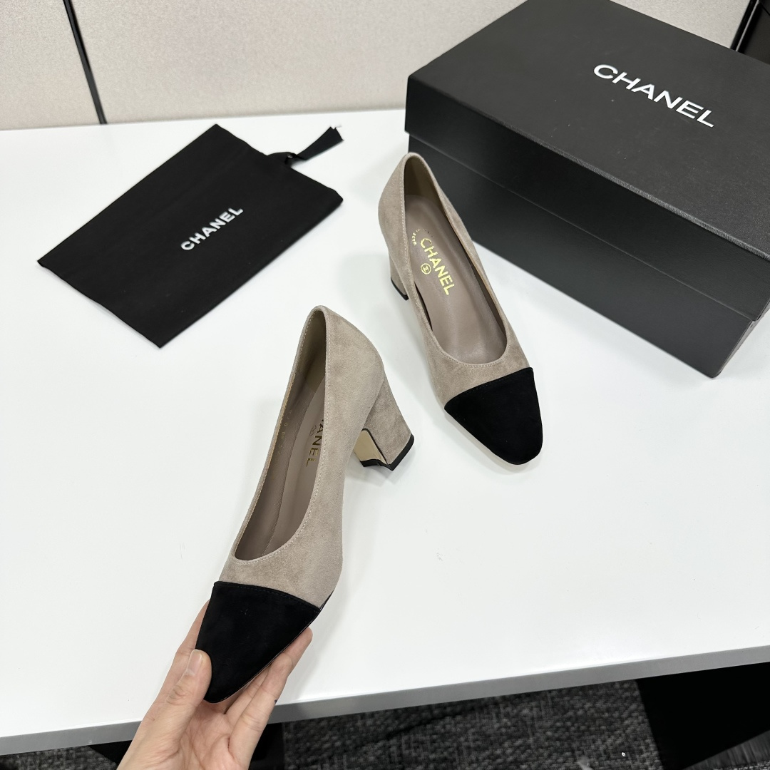 Elegant beige suede pumps with a black toe cap and gold logo on the block heel, displayed on a black designer box. - Hình 8
