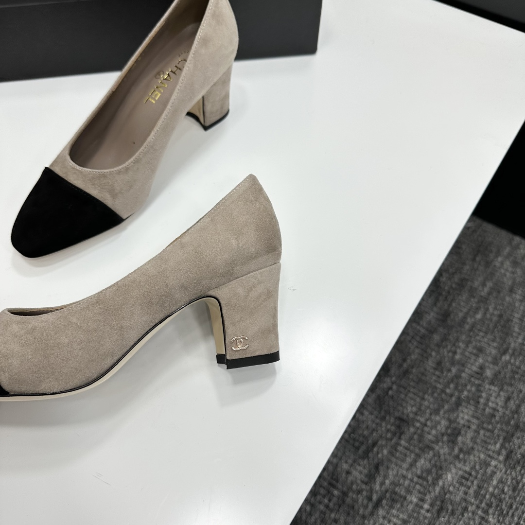Elegant beige suede pumps with a black toe cap and gold logo on the block heel, displayed on a black designer box. - Hình 6