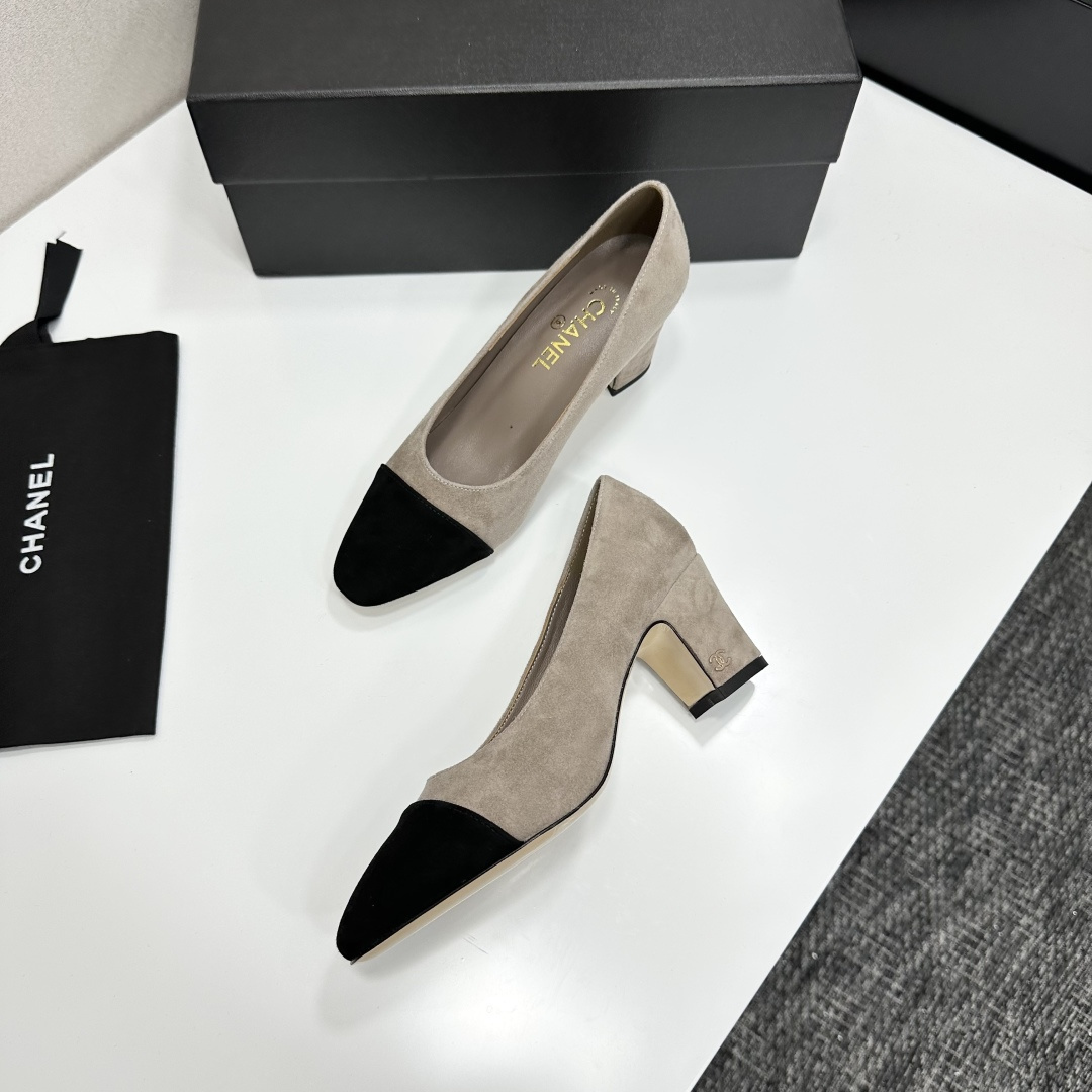 Elegant beige suede pumps with a black toe cap and gold logo on the block heel, displayed on a black designer box. - Hình 5