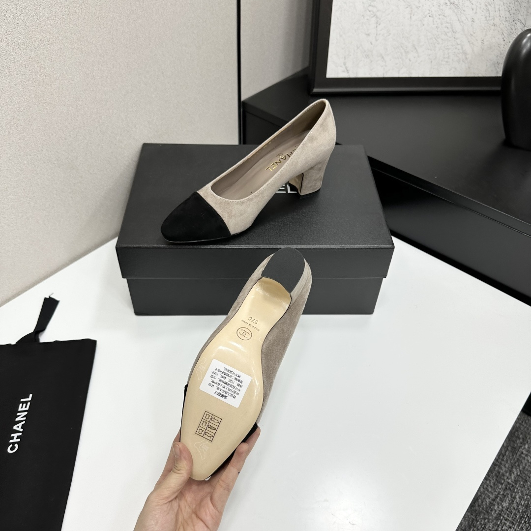 Elegant beige suede pumps with a black toe cap and gold logo on the block heel, displayed on a black designer box. - Hình 4