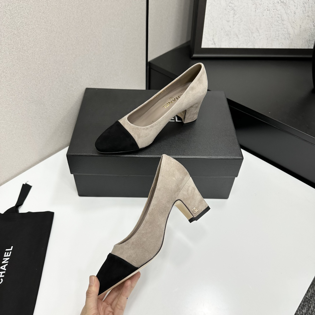 Elegant beige suede pumps with a black toe cap and gold logo on the block heel, displayed on a black designer box. - Hình 3