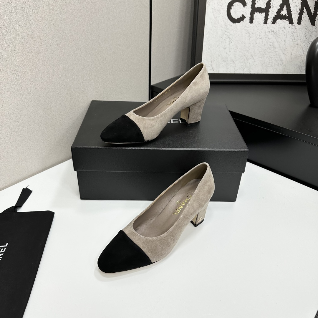Elegant beige suede pumps with a black toe cap and gold logo on the block heel, displayed on a black designer box. - Hình 2