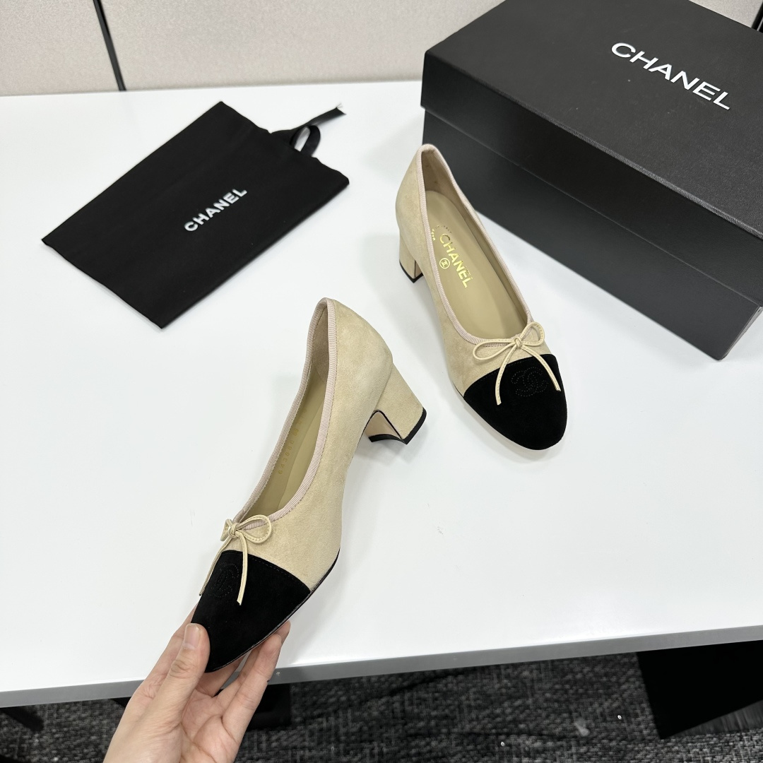 Elegant two-tone beige and black suede block heel pumps with a small bow detail on a black designer box. - Hình 9