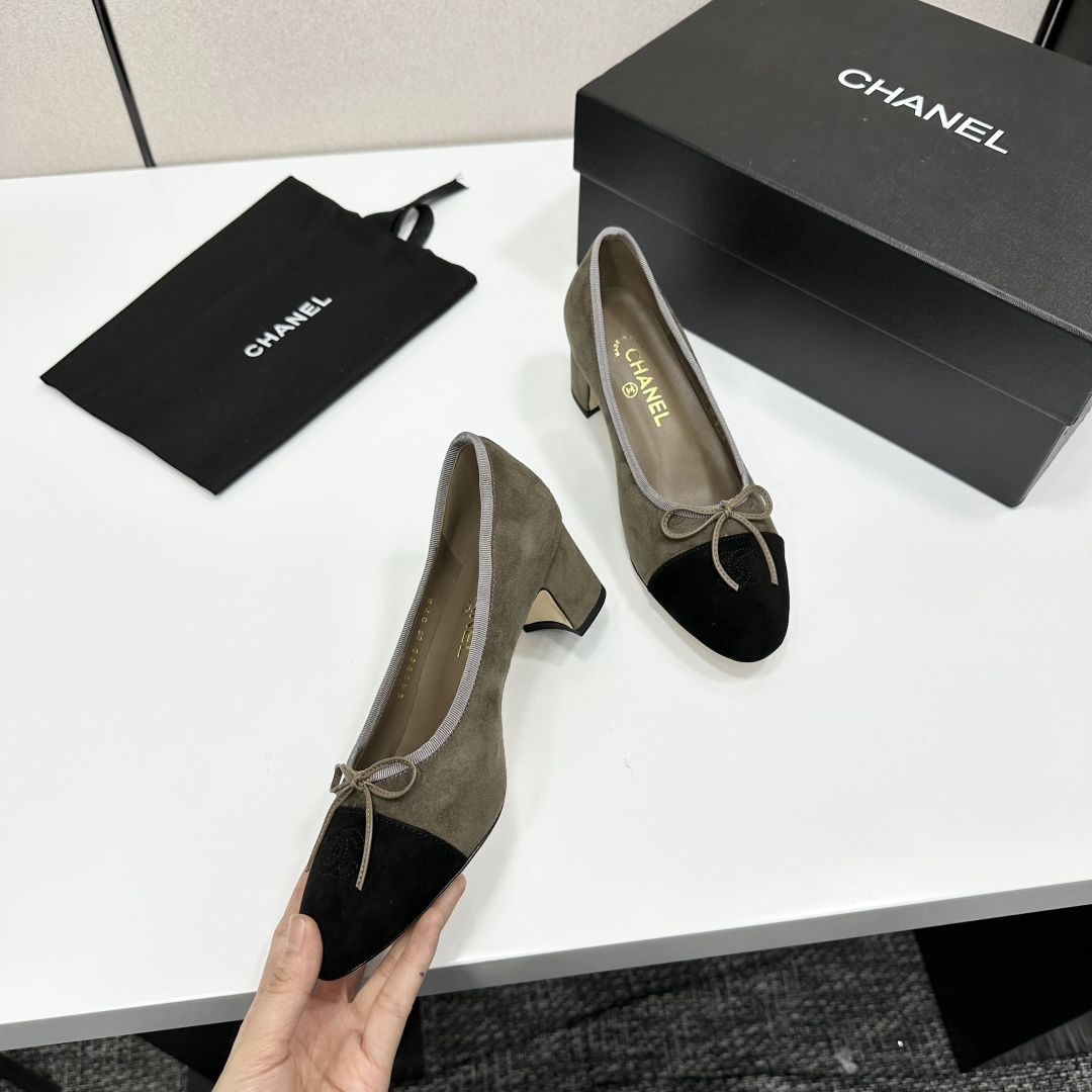A pair of Chanel two-tone khaki and black suede pumps with a block heel and bow detail displayed on a black box. - Hình 8